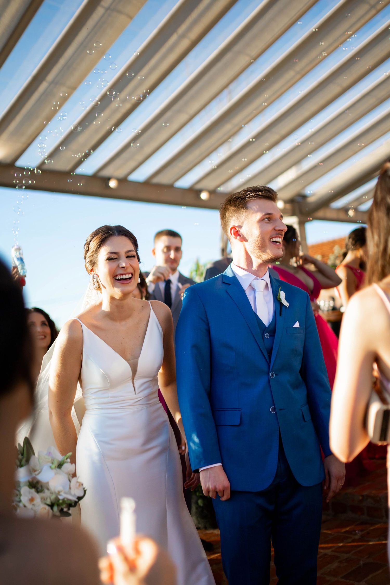 Joyful newlyweds laugh as they walk back down aisle surrounded by celebrating guests.