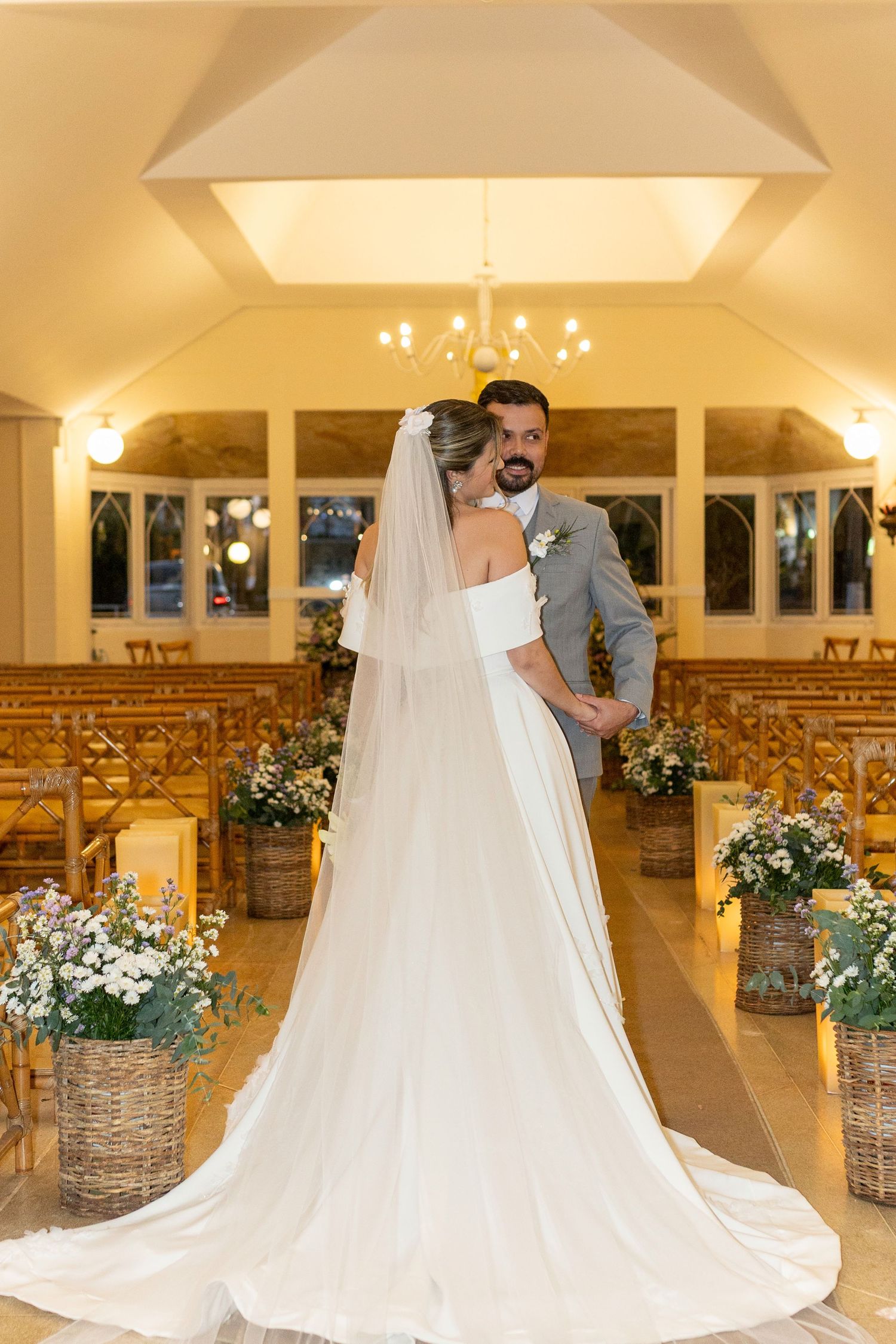 Bride and groom share a romantic moment at the altar of an elegant chapel decorated with floral arrangements.
