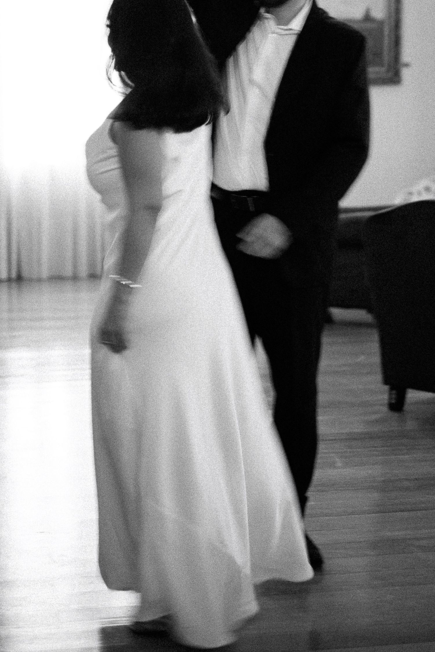 Black and white photo of a bride and groom sharing their first dance at a wedding reception.