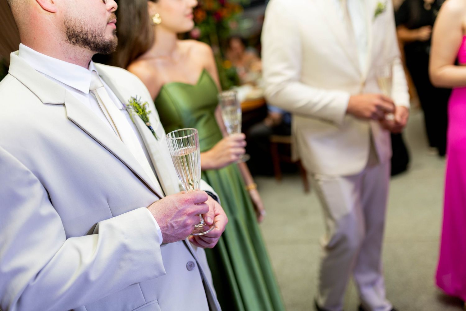 Wedding guests in formal attire holding champagne glasses at an elegant reception ceremony.