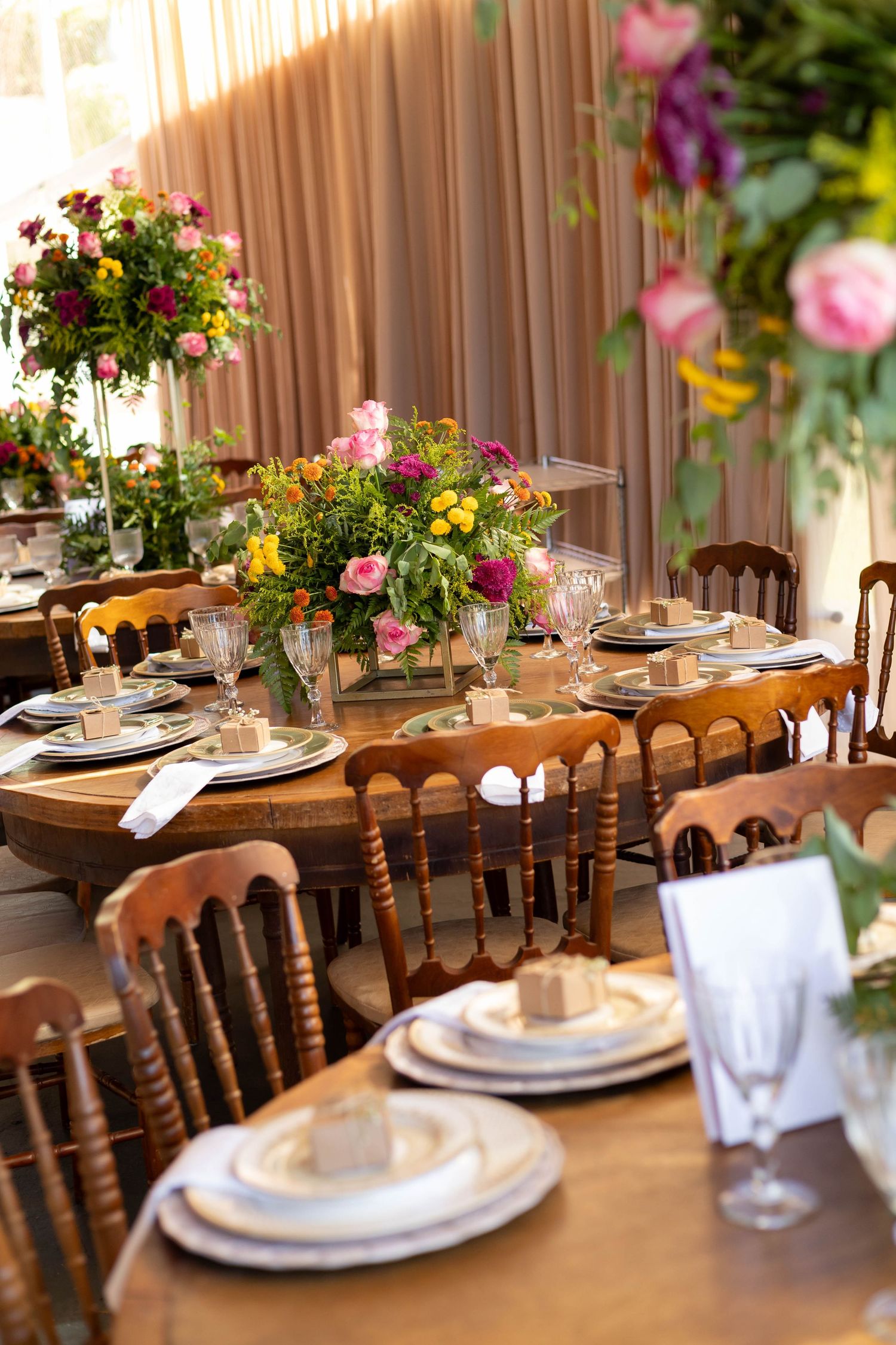 Elegant wooden dining table set with floral centerpieces, crystal glasses, and white plates for a formal event.