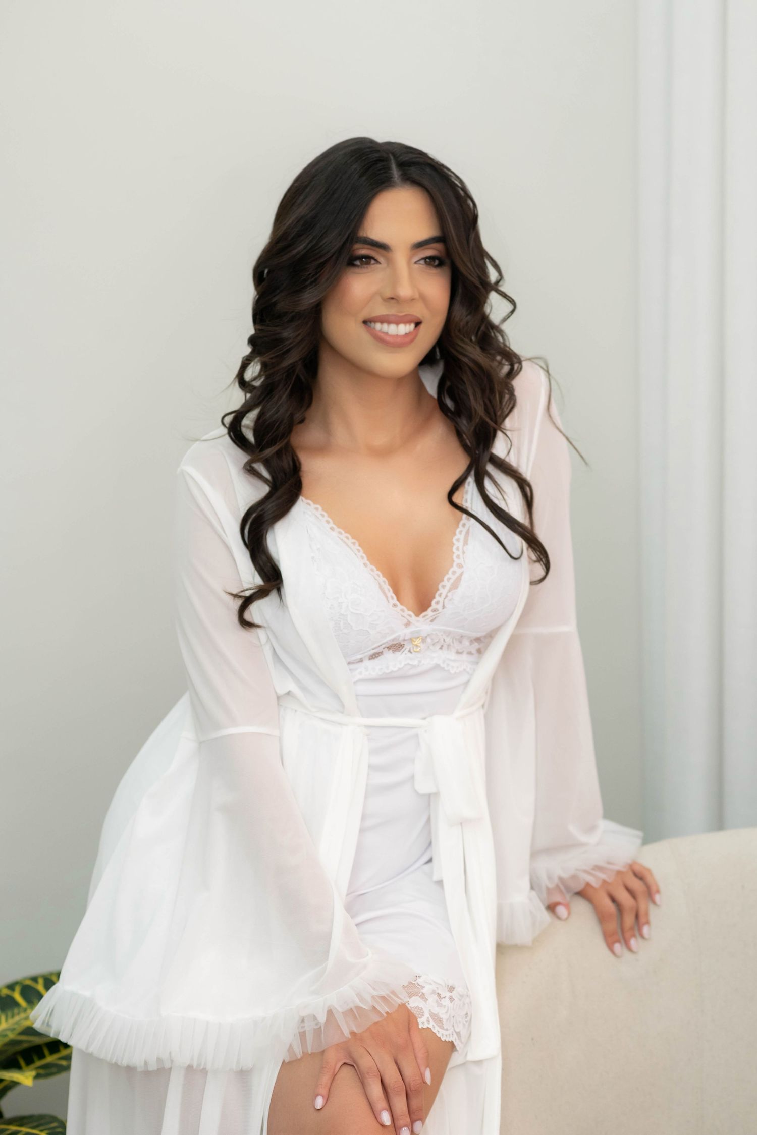 Woman in white lace bridal robe and lingerie smiling, elegant bridal boudoir portrait photography.