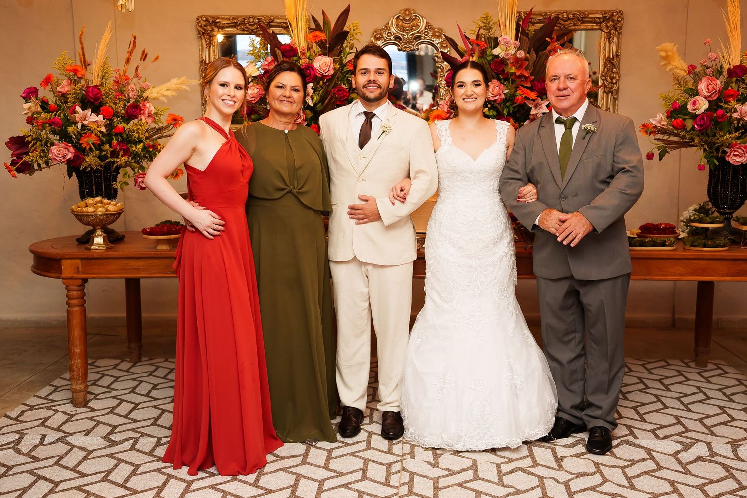 Wedding party of five posing elegantly in a decorated venue with floral arrangements.