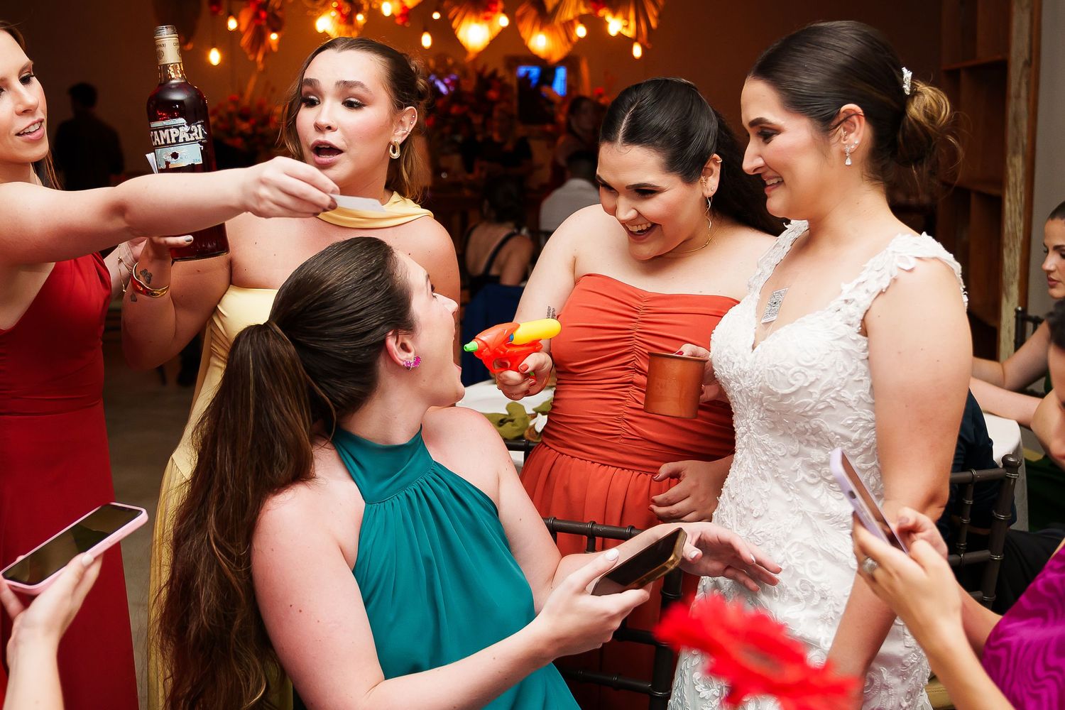 Bride in white gown celebrates with bridesmaids in colorful dresses at a lively wedding reception party.