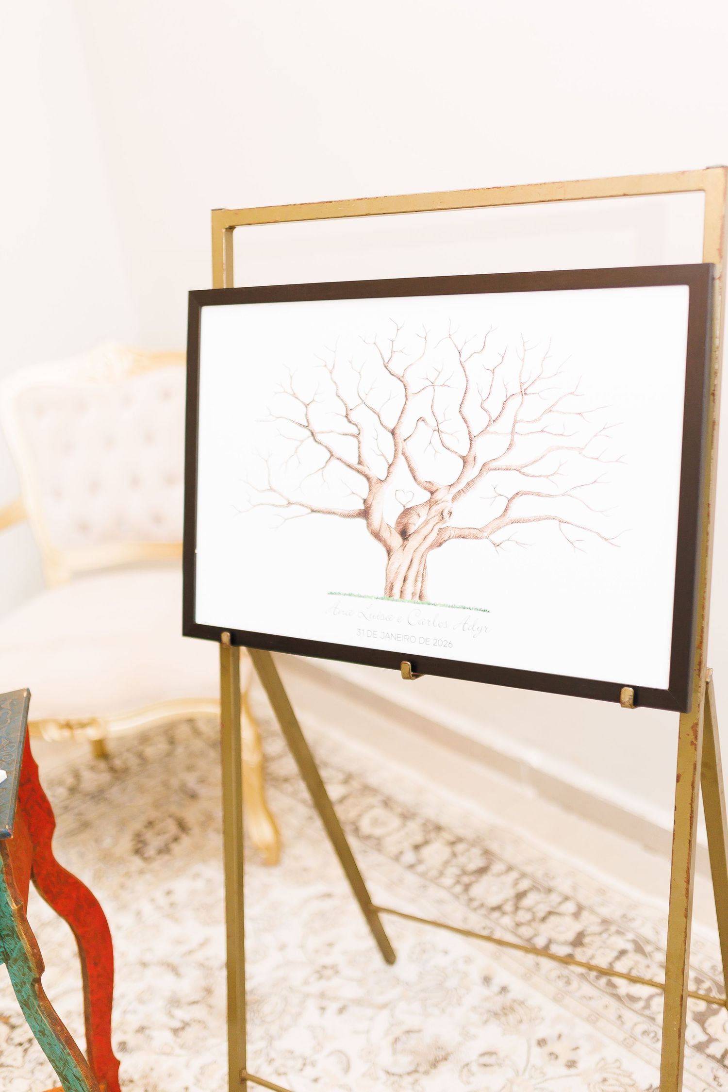 Gold easel displaying a fingerprint wedding guest book tree art print in a black frame at a wedding venue.