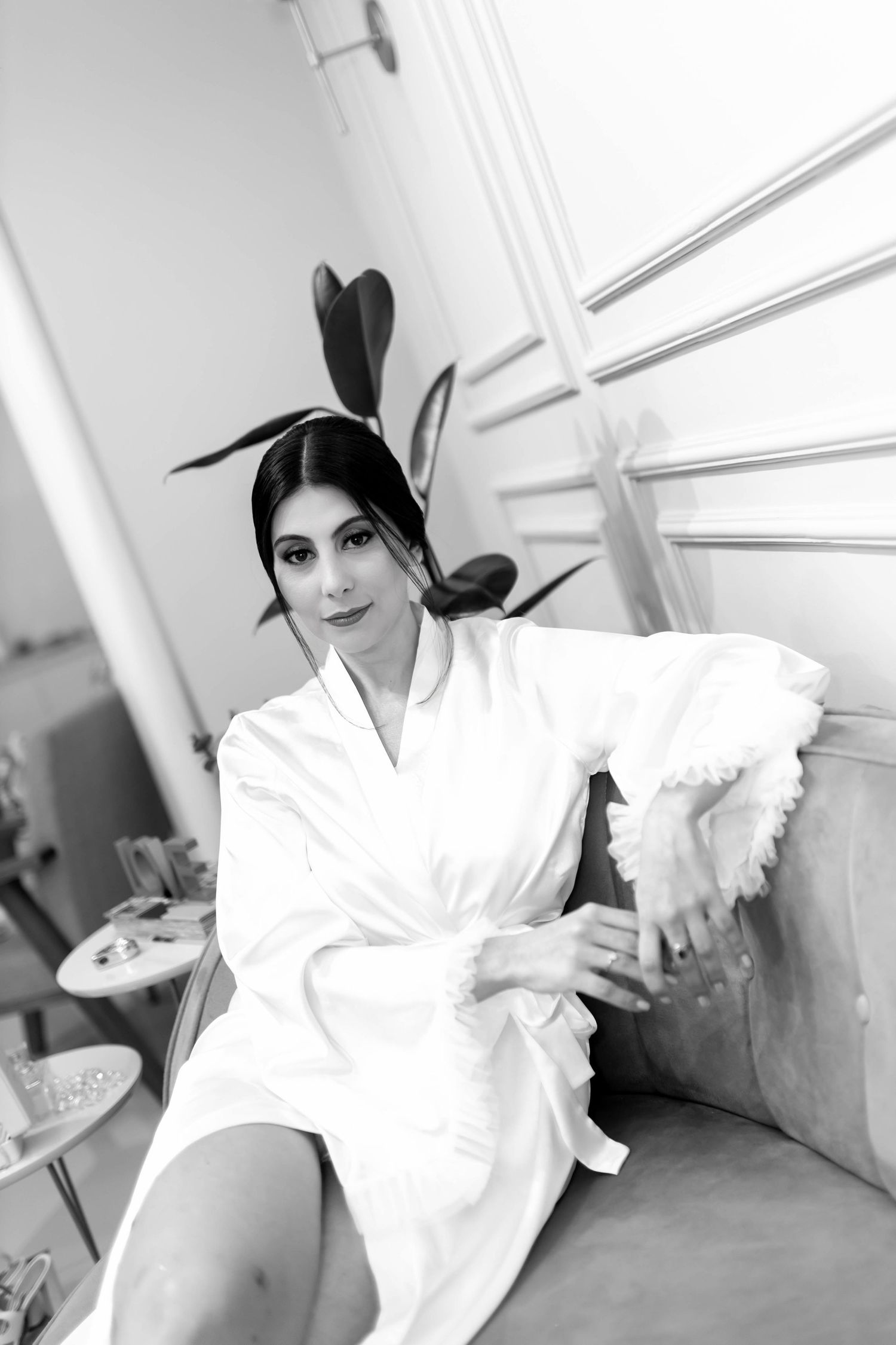 Black and white photo of a woman in a white robe with bunny ears sitting elegantly on a sofa.