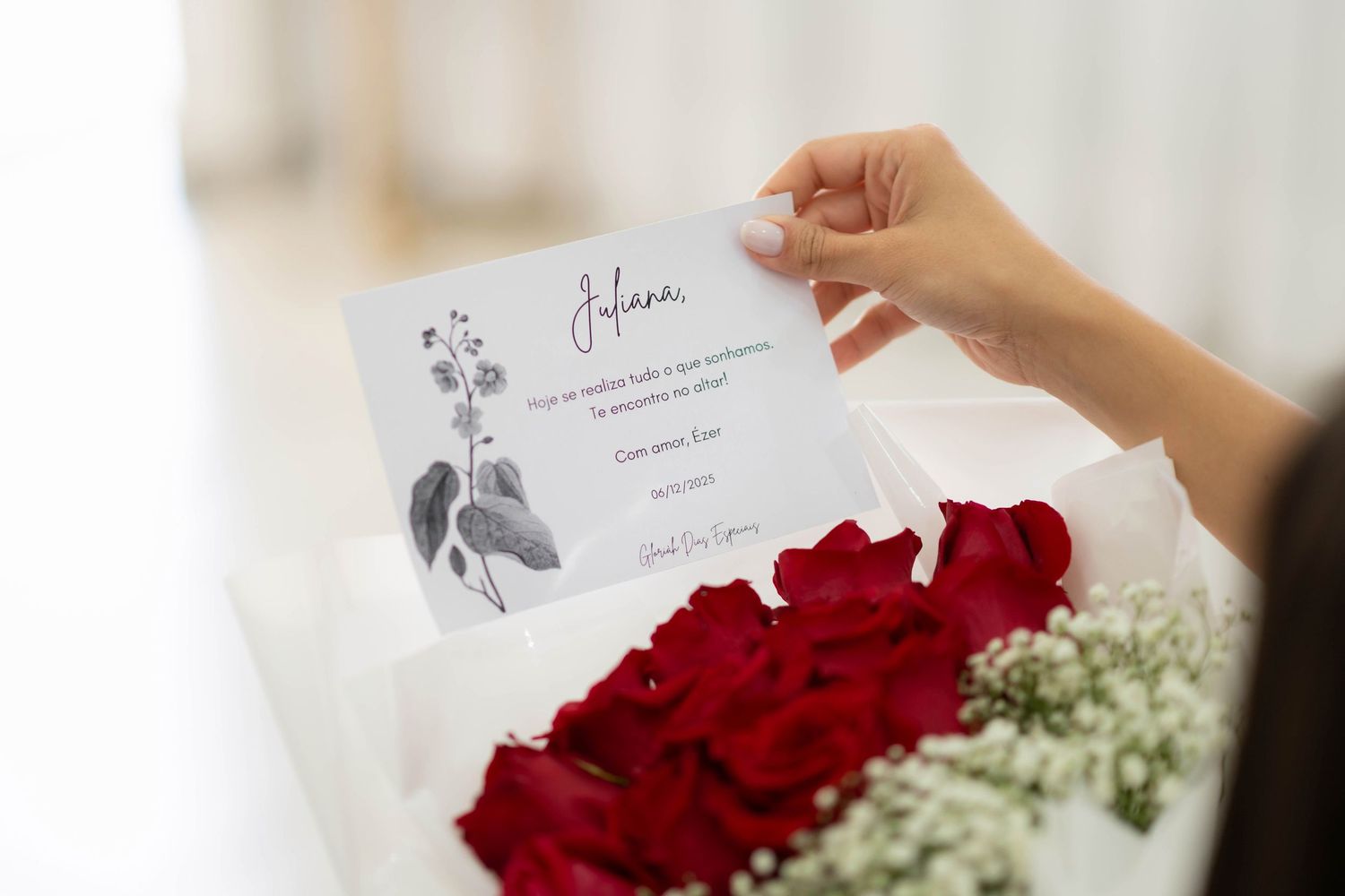 Hand holding a personalized card above a white box filled with red roses and baby's breath.