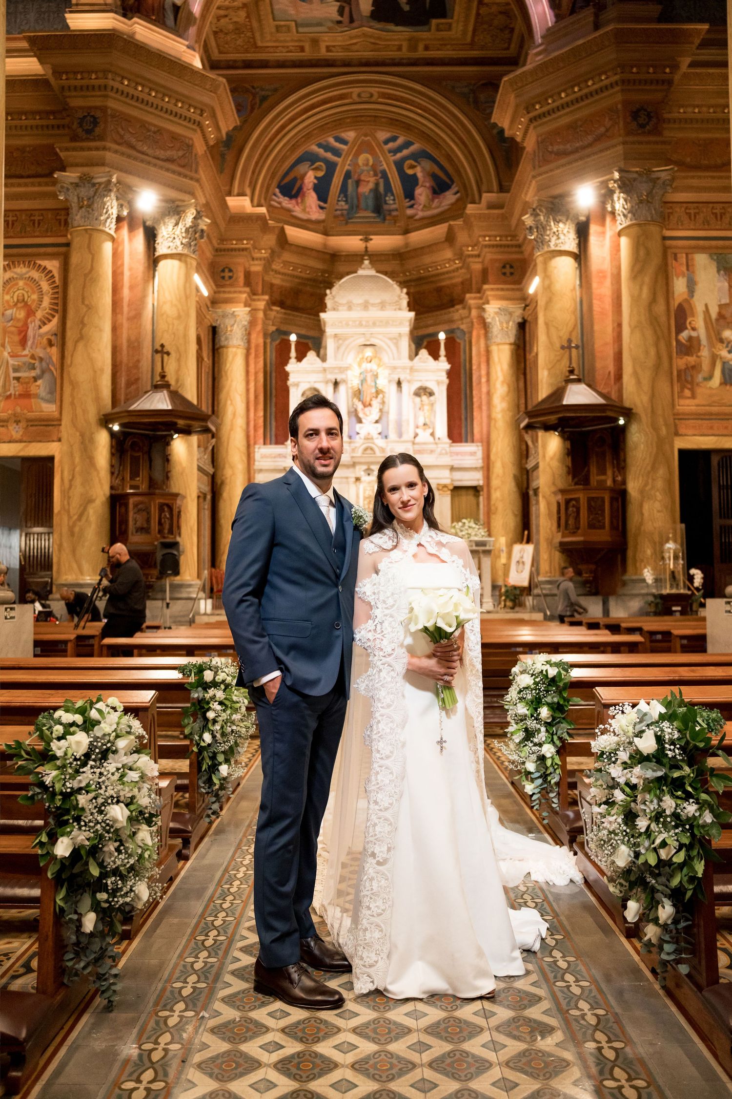 Bride and groom posing together at the altar of an ornate church after their wedding ceremony.