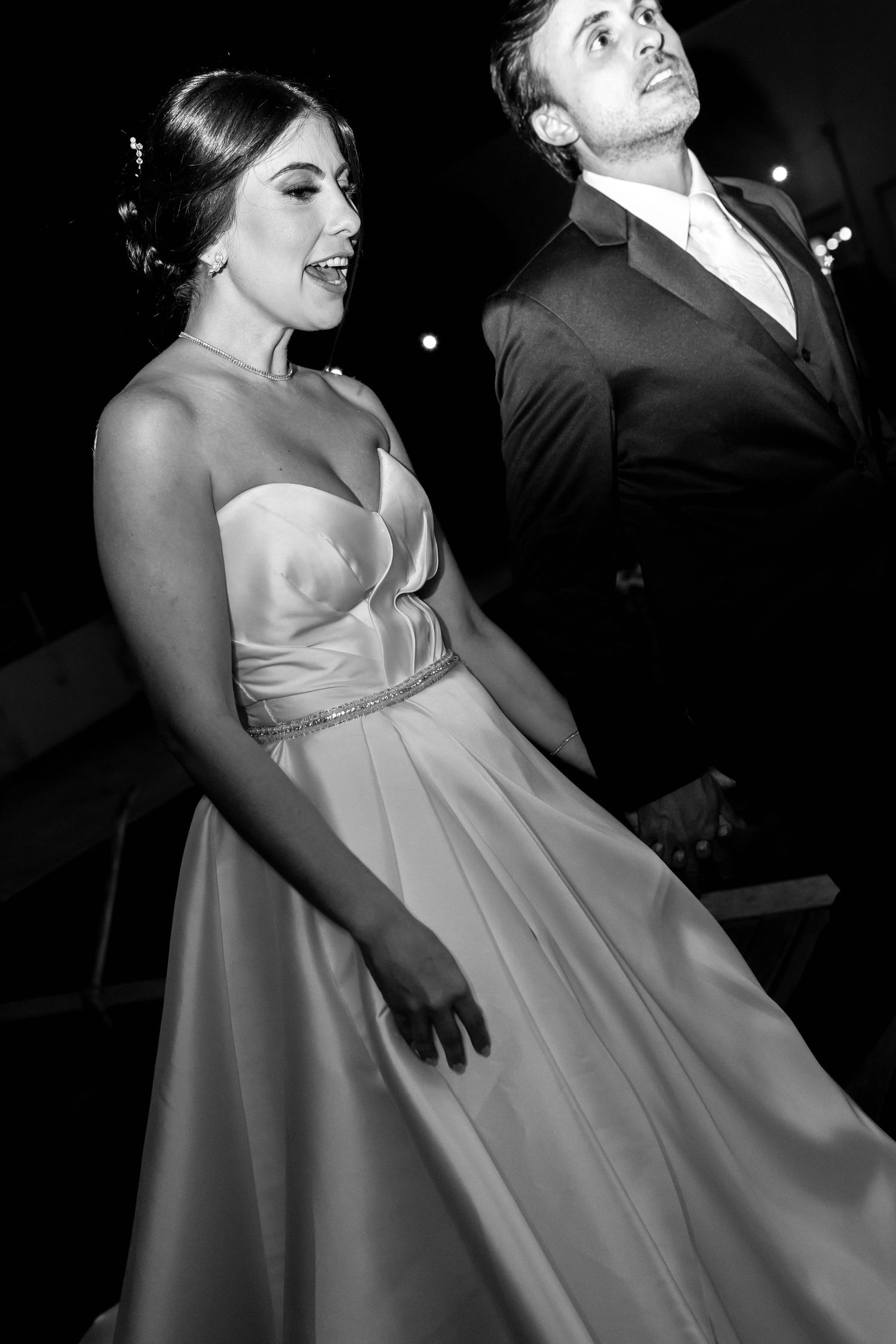 Black and white photo of a woman in elegant strapless gown and man in suit at a formal event.