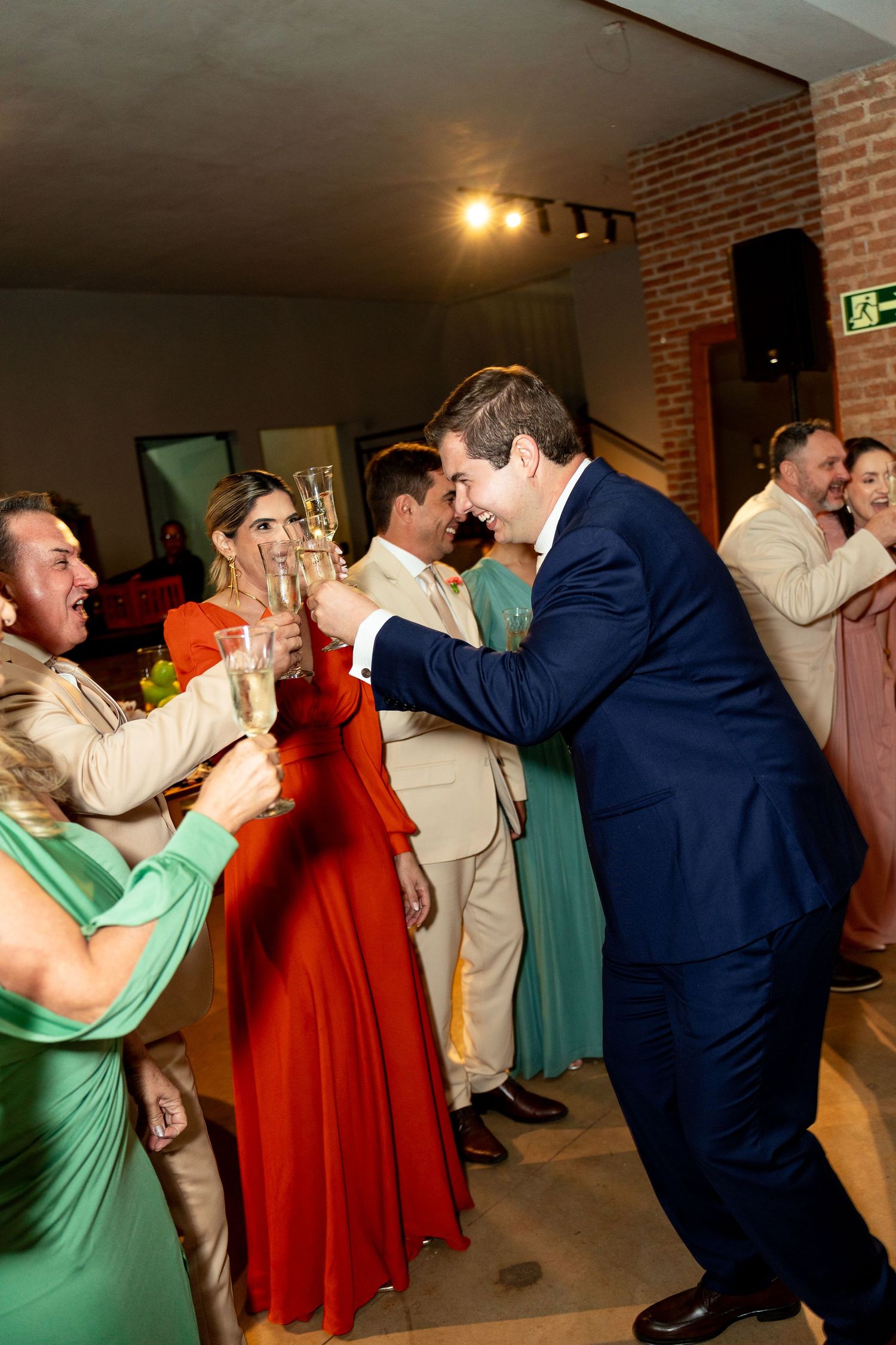 Wedding guests in formal attire toasting with champagne glasses on the dance floor during a festive celebration.