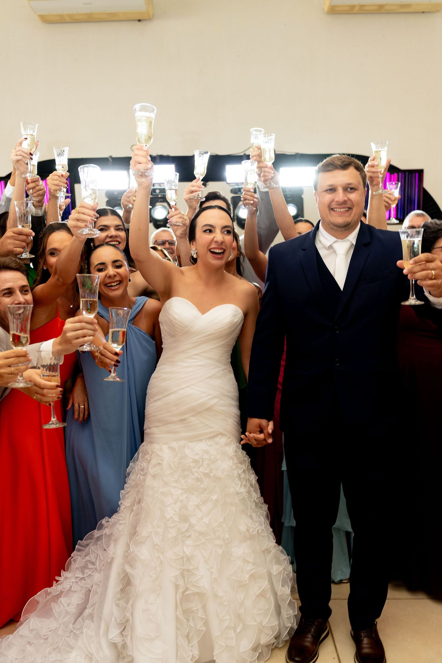 Bride and groom raise champagne glasses with wedding guests during a joyful reception toast celebration.