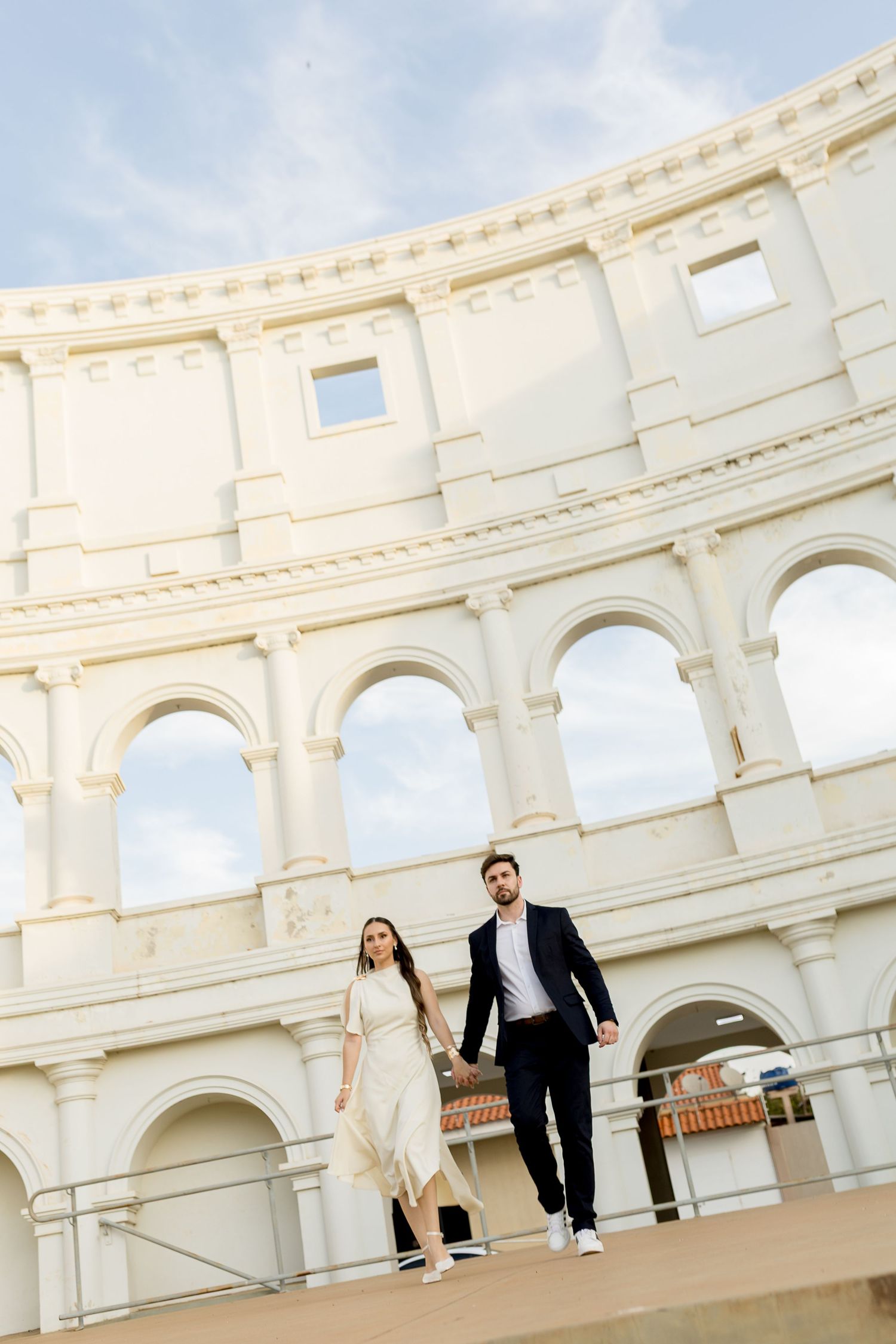 Couple holding hands in front of the Colosseum in Rome, Italy, on a sunny day.