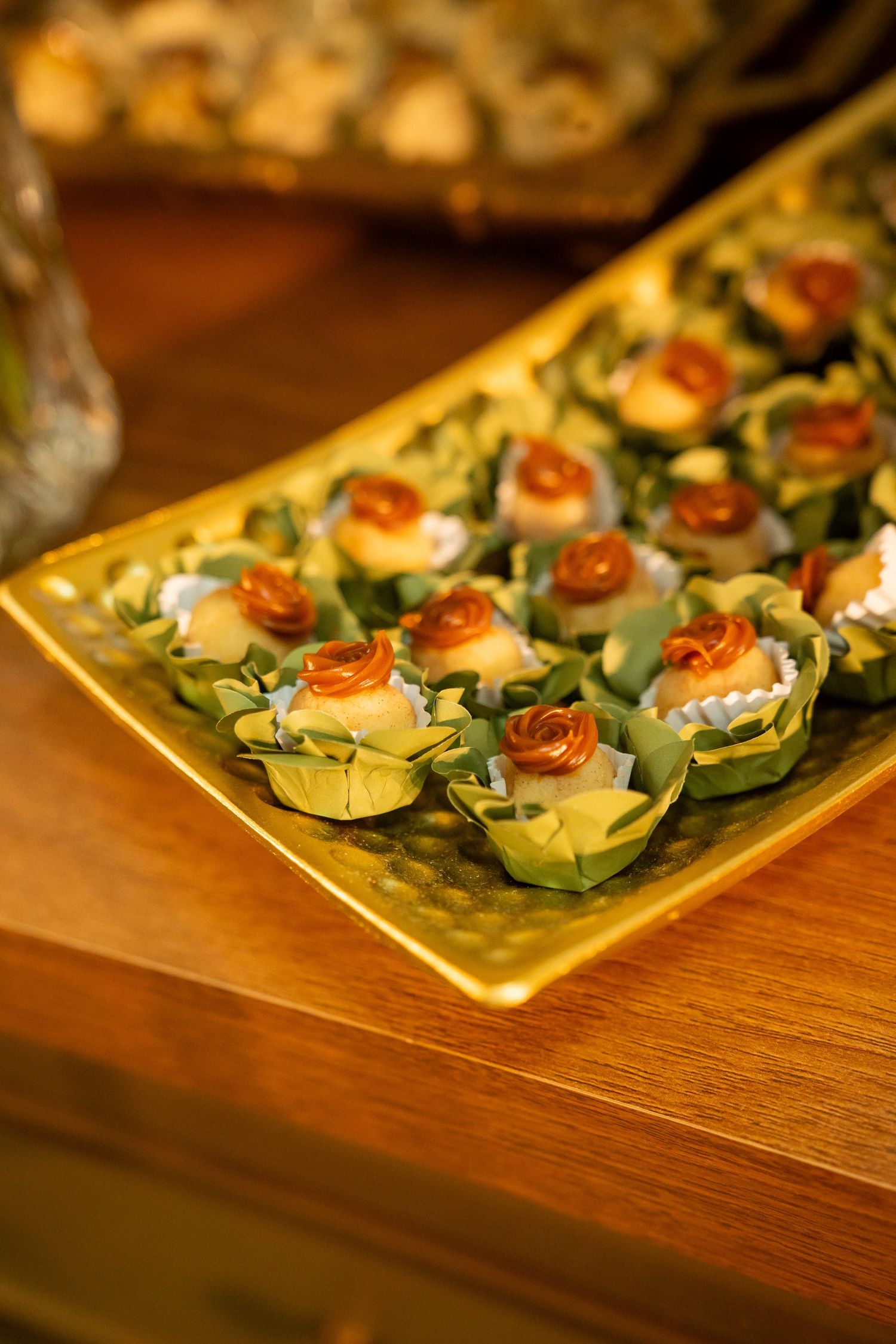 Elegant gold tray of bite-sized appetizers topped with decorative rose garnishes, served at a formal catered event.