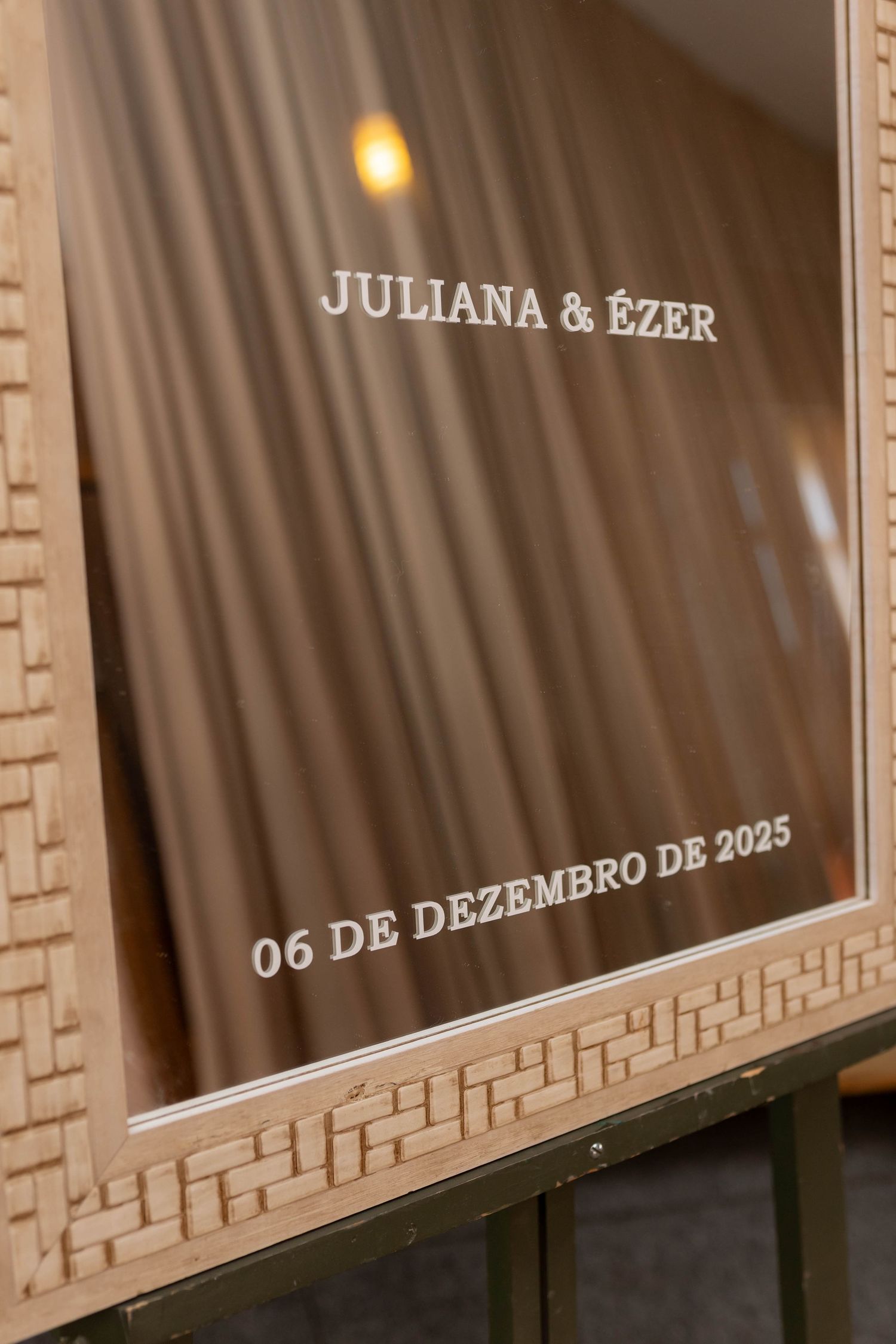 Elegant wedding sign for Juliana and Ézer, dated 06 de Dezembro de 2025, displayed in a decorative beige frame.
