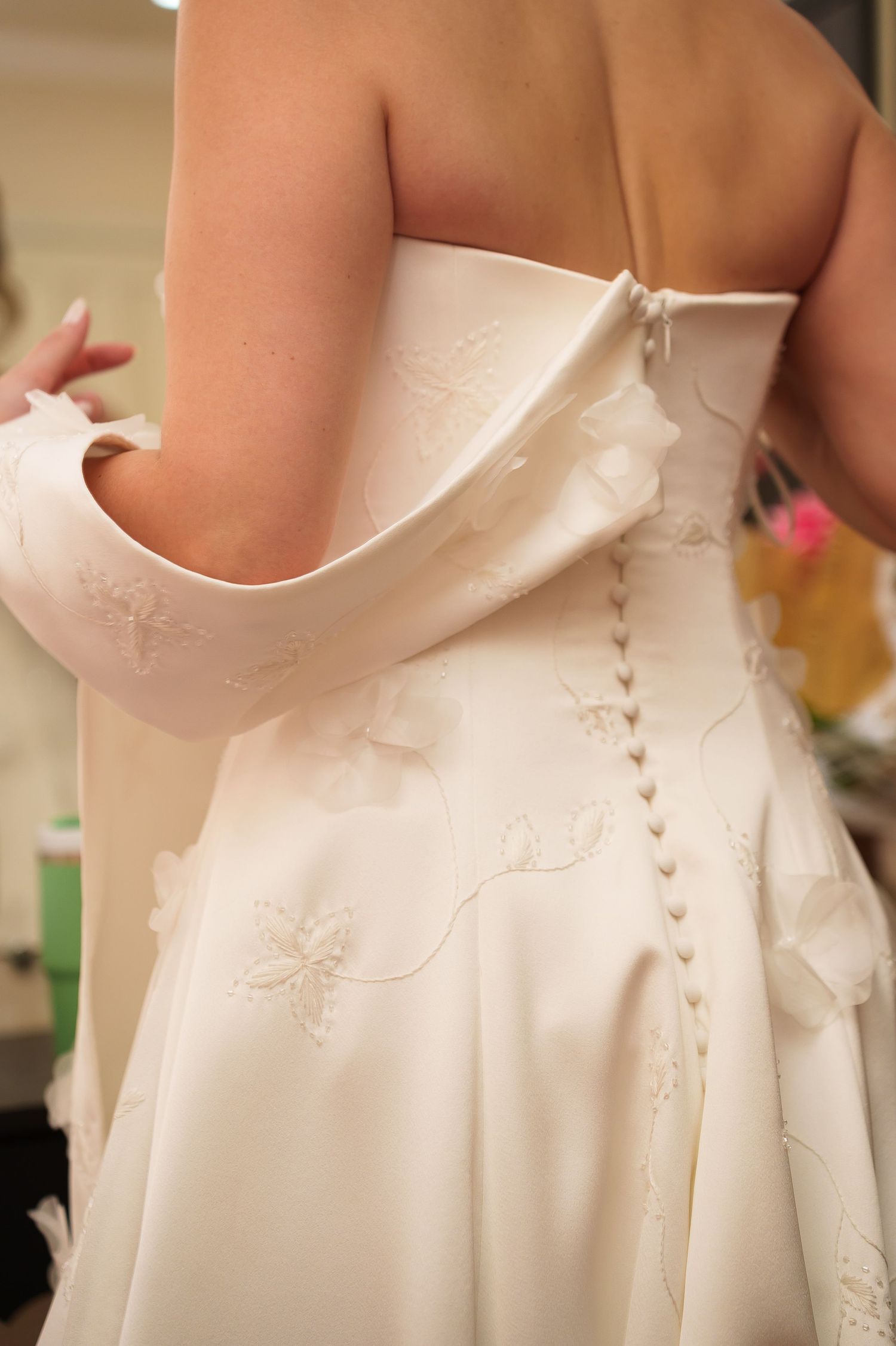 Bride in a white strapless wedding gown with embroidered floral details and delicate button back closure.