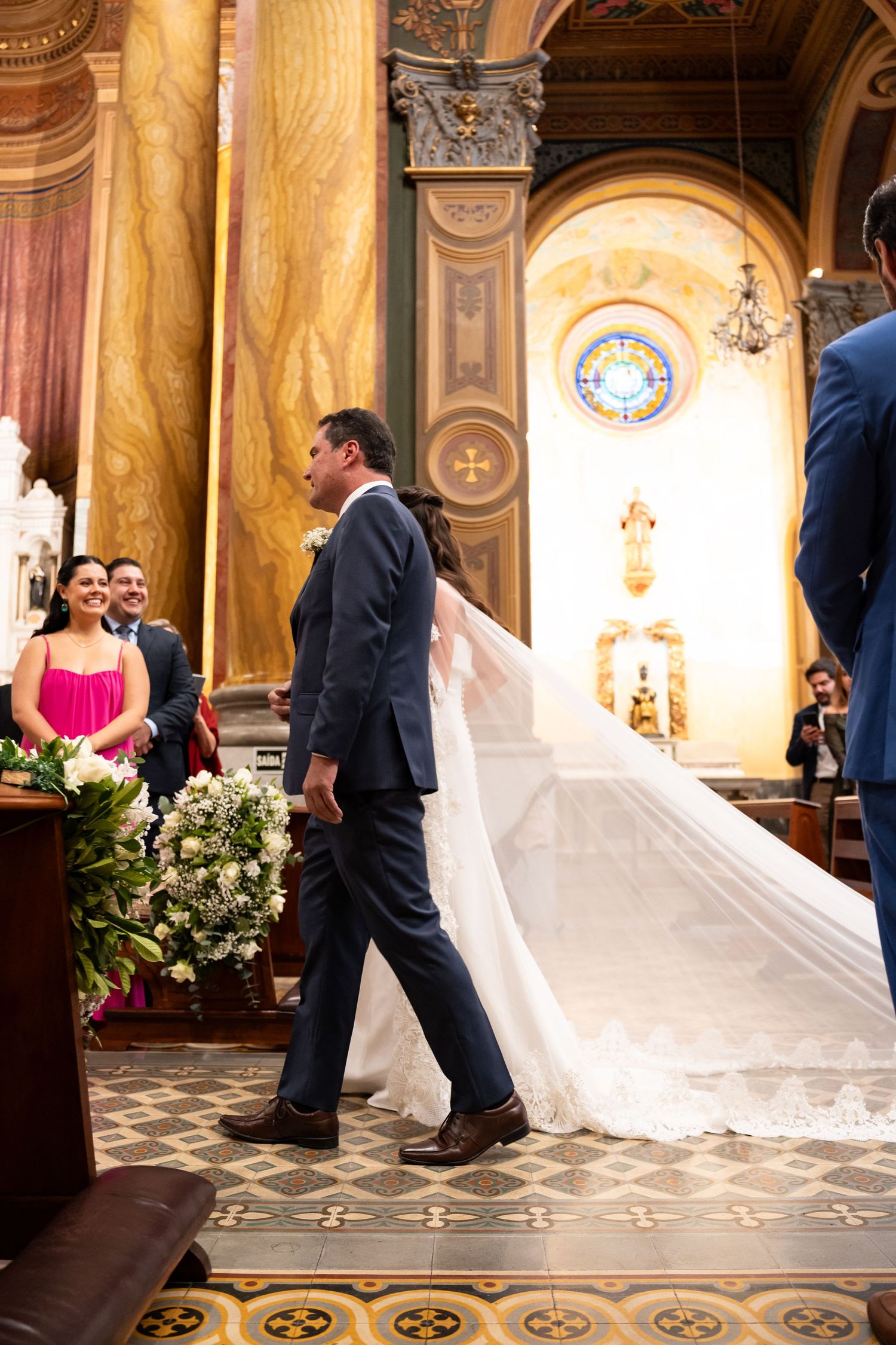 Bride and groom walking down the aisle of an ornate church during a wedding ceremony.