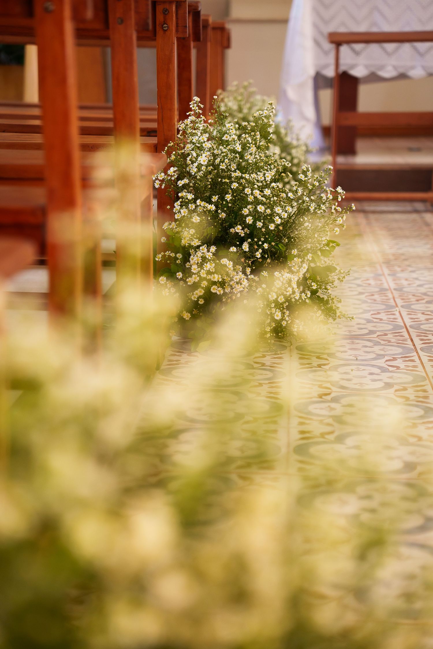 White wildflowers decorating church pew ends along a tiled aisle for a wedding ceremony.