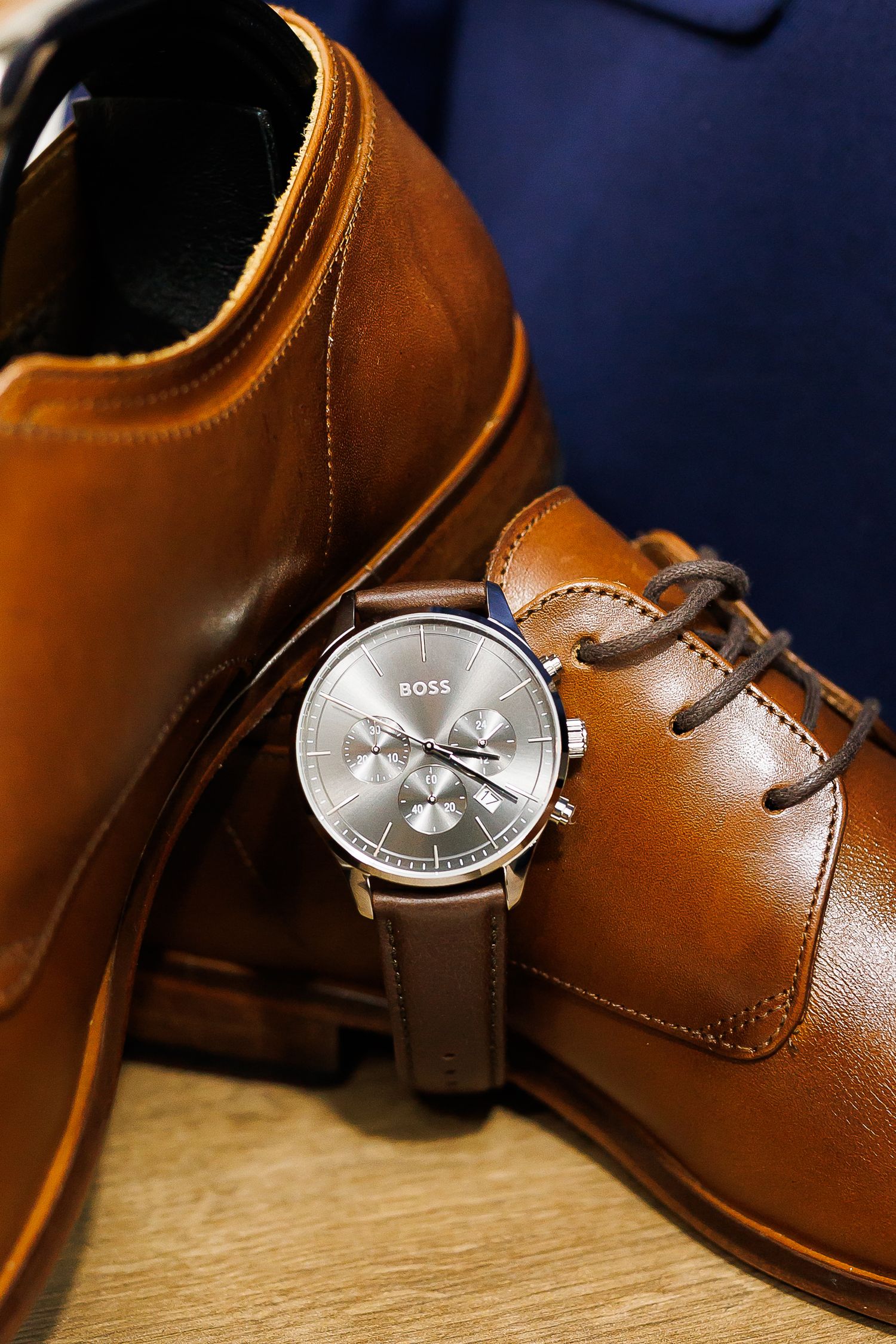 Hugo Boss chronograph watch with brown leather strap resting on tan leather dress shoes.