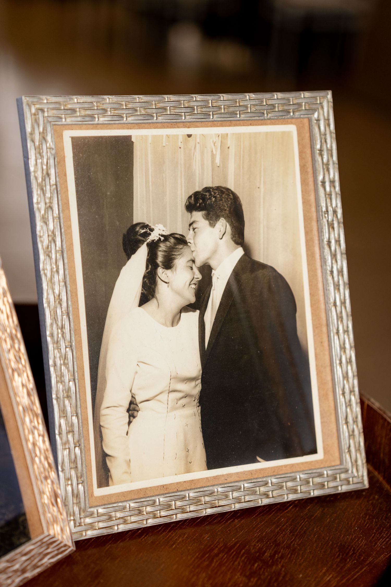Vintage sepia wedding photo in a woven silver frame showing a bride and groom sharing a kiss.
