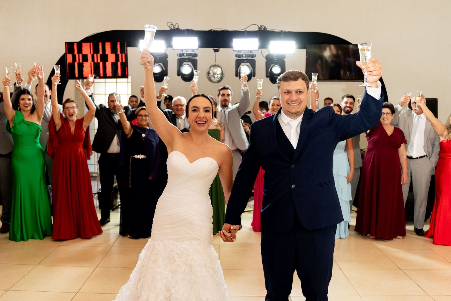 Bride and groom celebrate first dance at wedding reception with guests cheering in background.