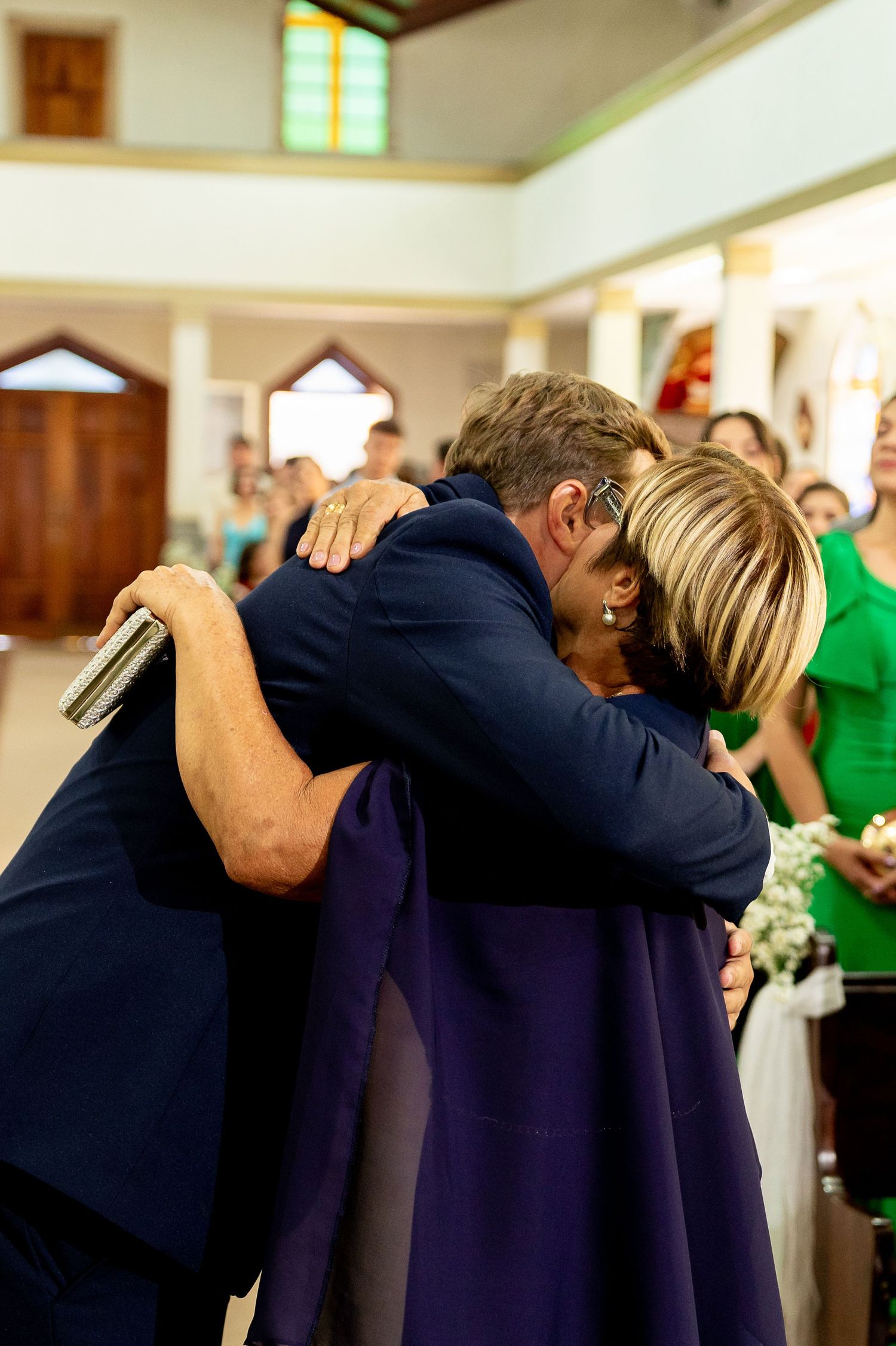 Two people share an emotional hug during a wedding ceremony inside a church.
