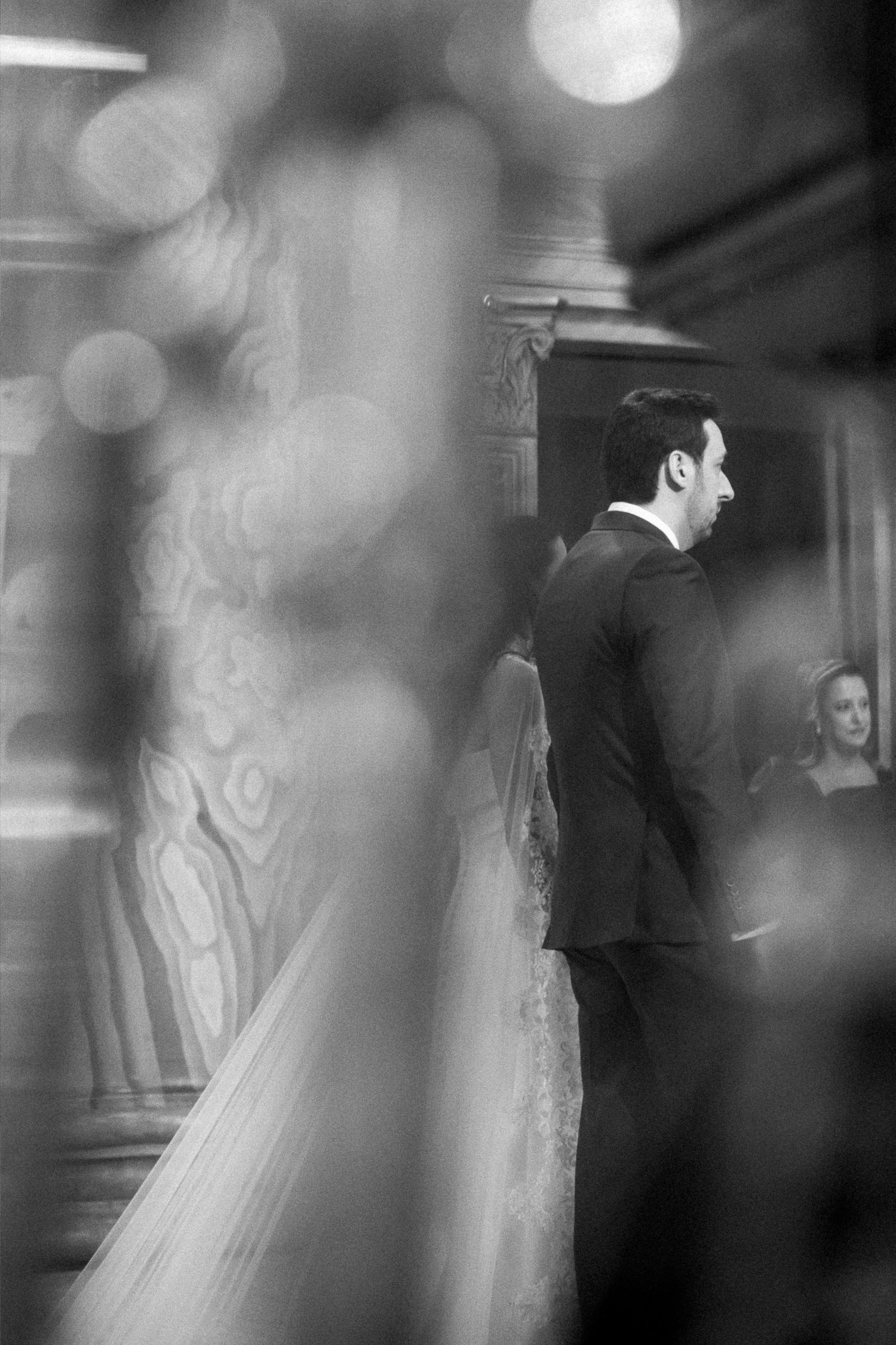 Black and white wedding photo of bride and groom standing at altar during elegant ceremony.