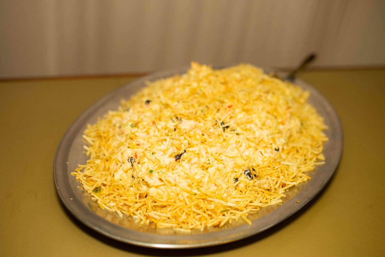 A large silver platter filled with fluffy yellow saffron rice garnished with fried onions, served as a traditional biryani dish.