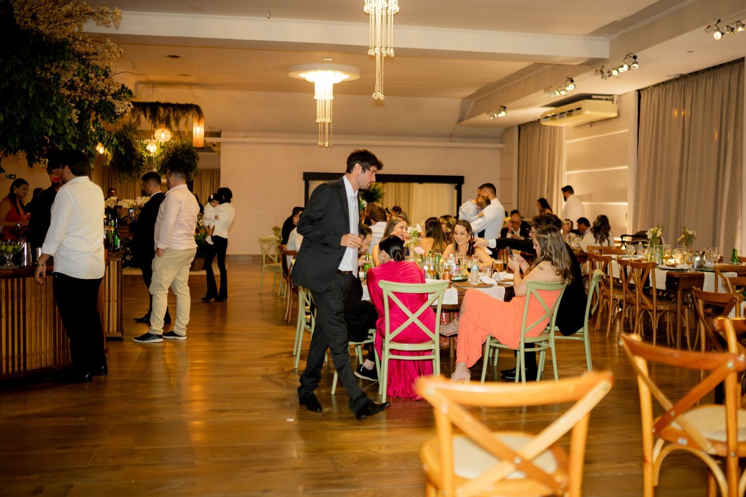 Elegant indoor dining event with guests seated at colorful chairs around decorated tables in a modern restaurant.