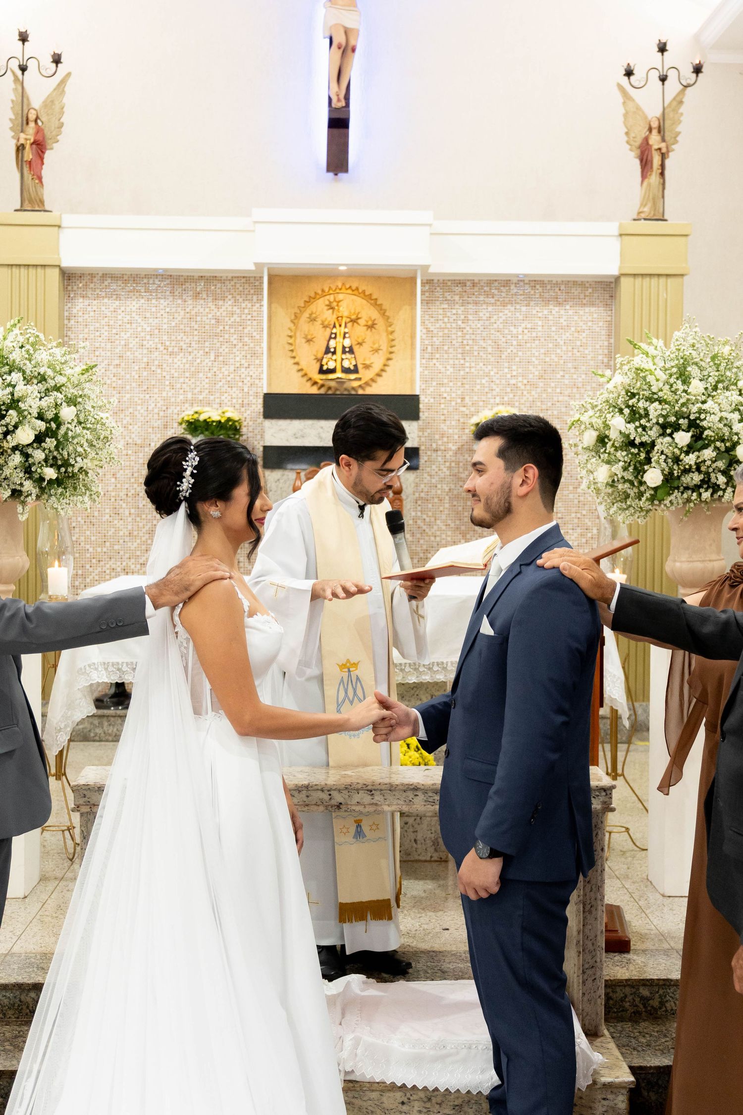 Bride and groom exchange vows at church altar with priest officiating during a traditional Catholic wedding ceremony.