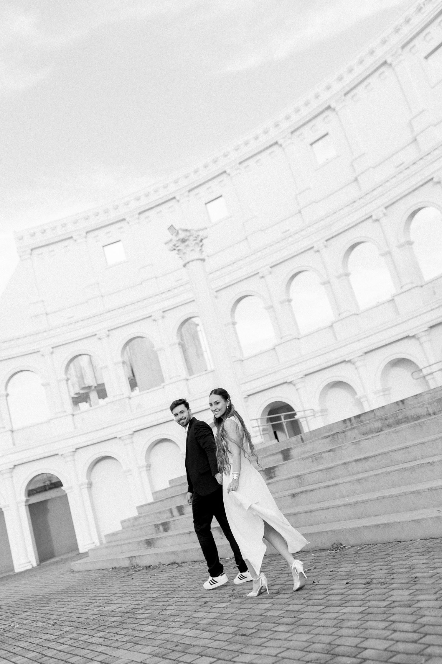 Black and white photo of a couple posing in front of the Colosseum in Rome, Italy.