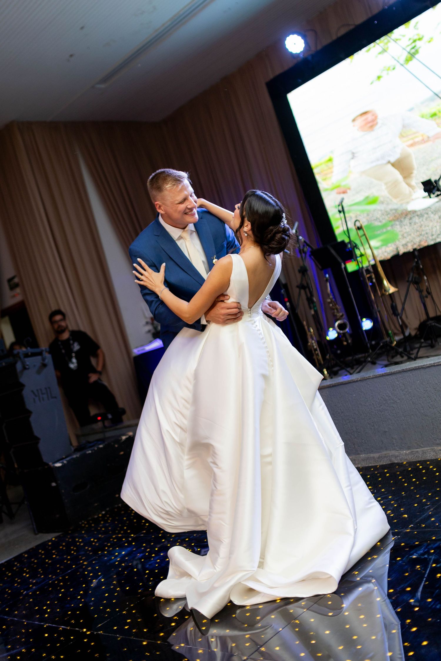 Bride and groom share their first dance on a starry black dance floor at an elegant wedding reception venue.