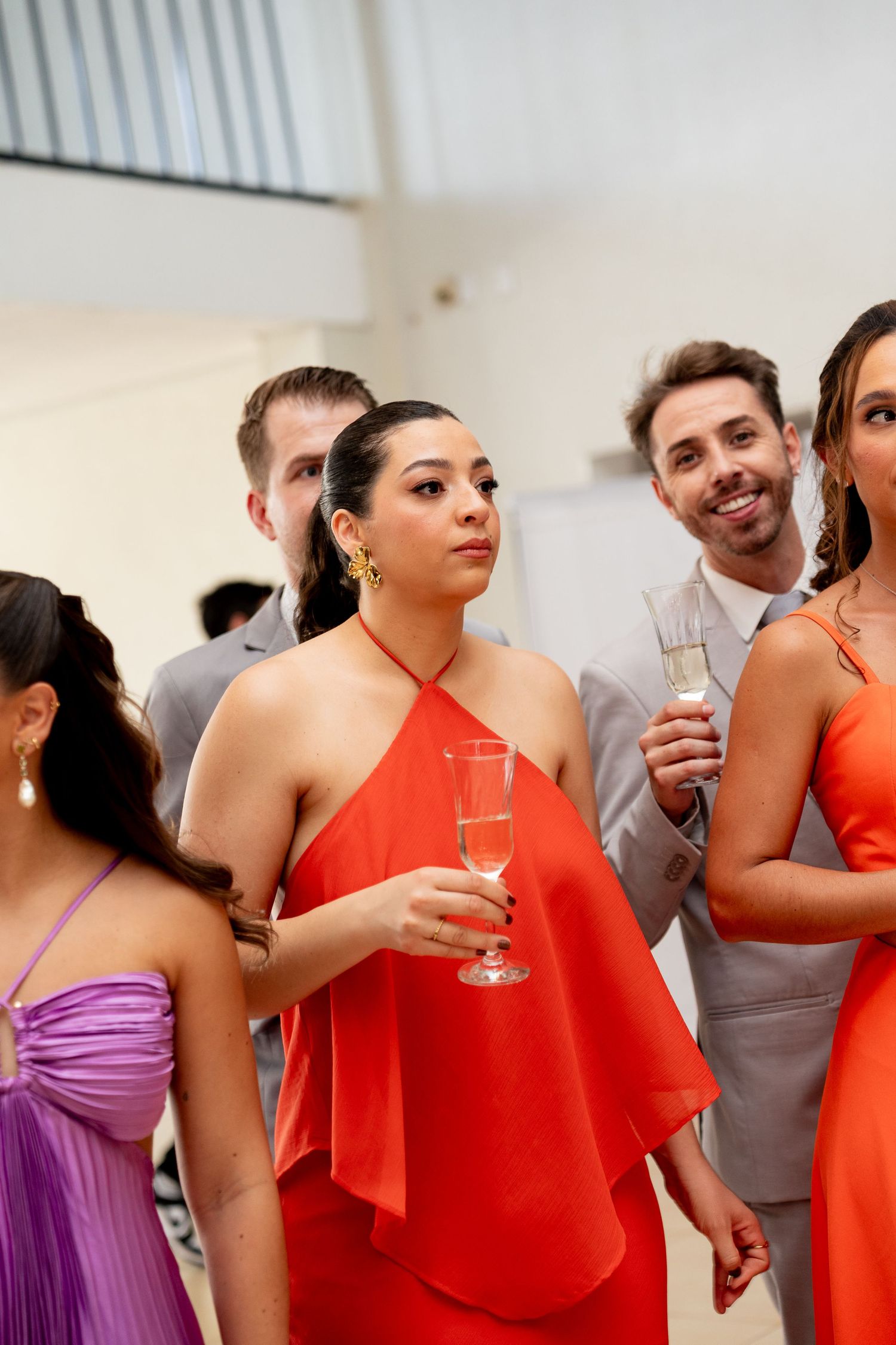 Elegant guests in red and purple gowns holding champagne flutes at a formal event.