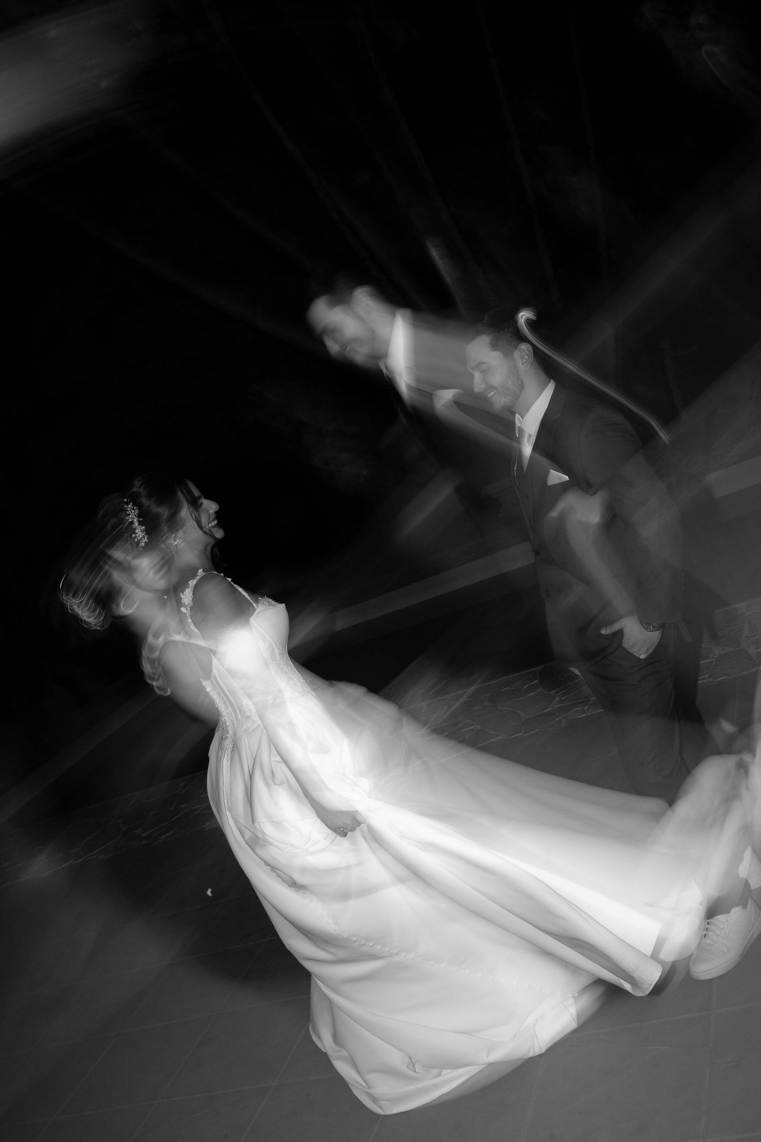 Black and white motion blur photo of bride and groom sharing first dance at wedding reception.
