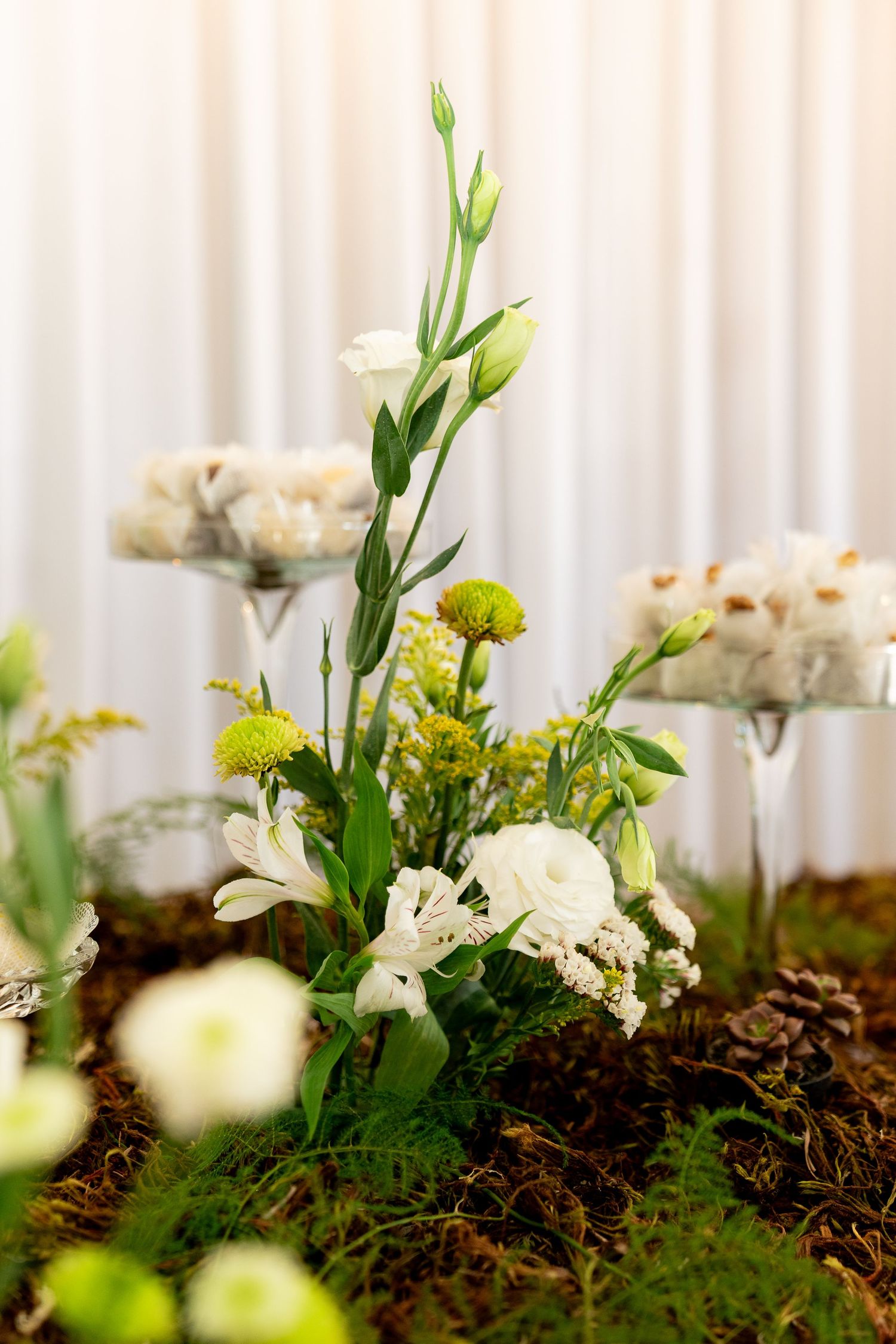 White and green wedding floral centerpiece with lisianthus, alstroemeria, and chrysanthemums on a natural moss base.