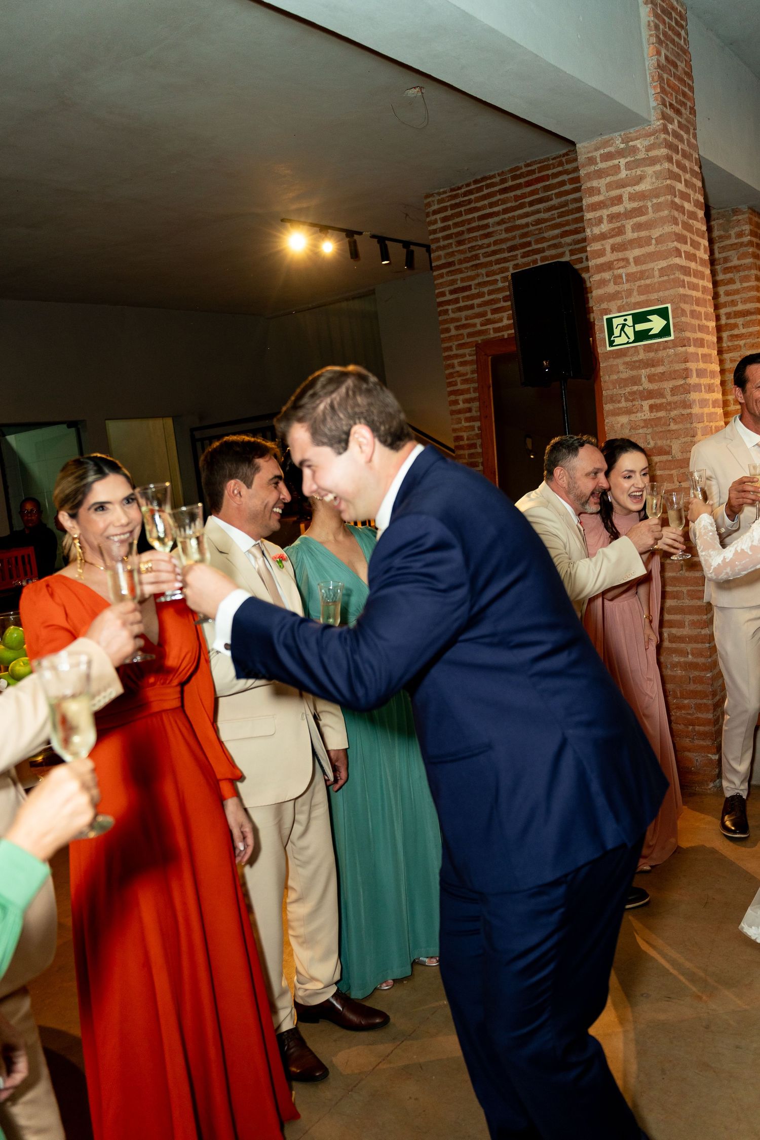 Guests in formal attire toasting with champagne glasses at an elegant indoor wedding reception celebration.