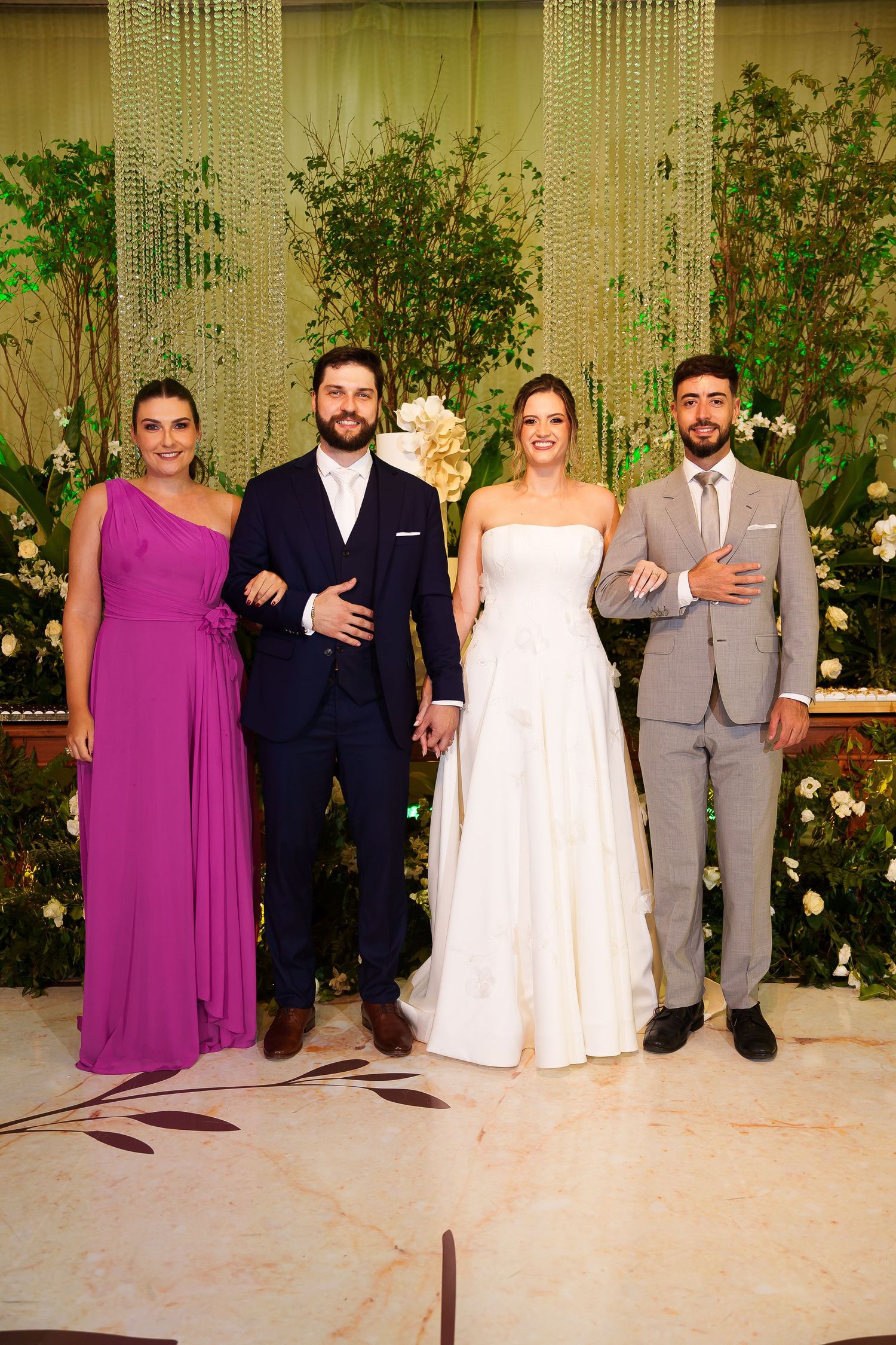Wedding party poses with bride in white gown, groom in navy suit, bridesmaid in purple dress, and groomsman in gray suit.