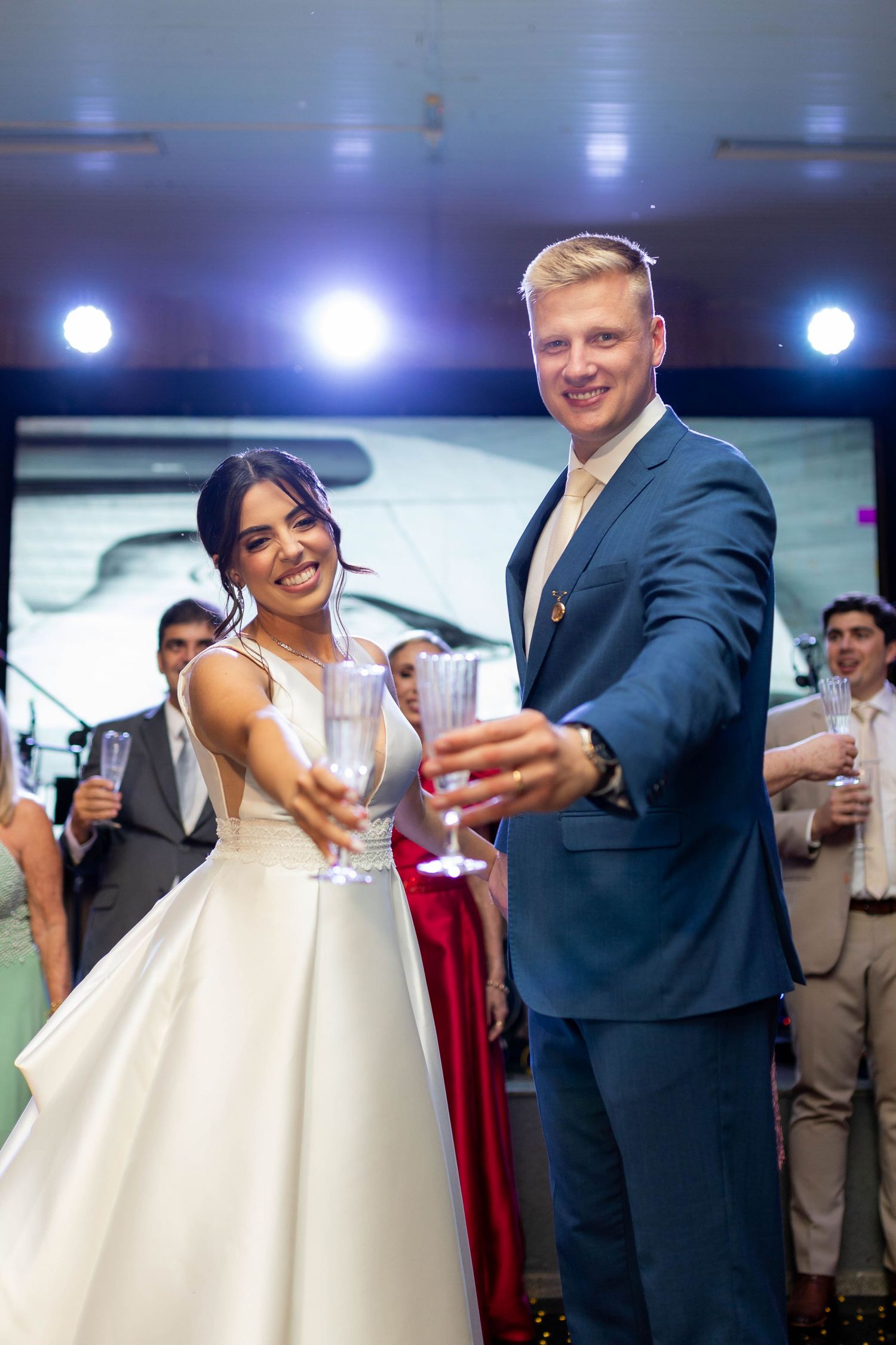 Smiling bride and groom toasting with champagne glasses at their wedding reception celebration.