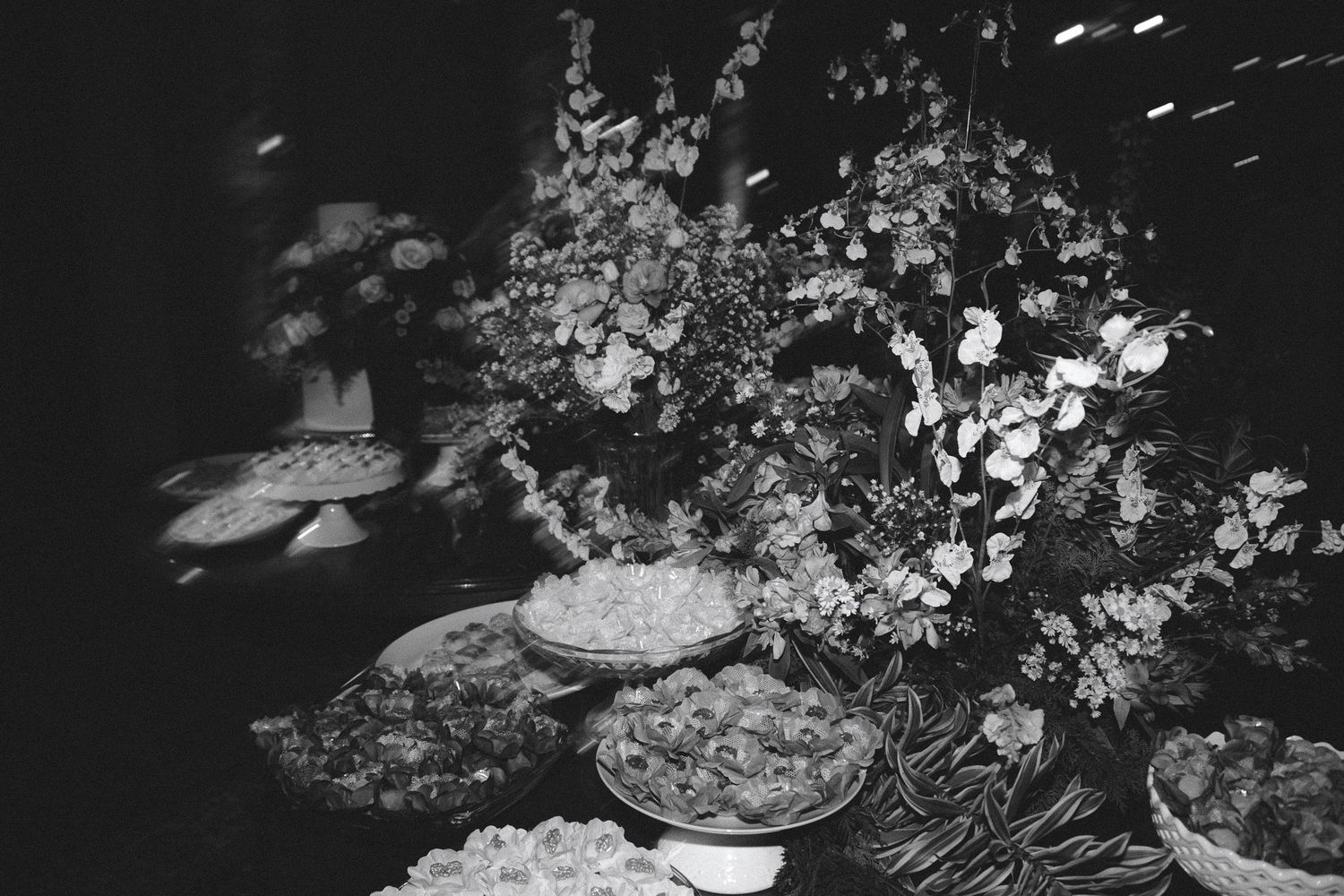 Black and white photo of an elegant buffet table with floral arrangements and assorted dishes at a formal event.