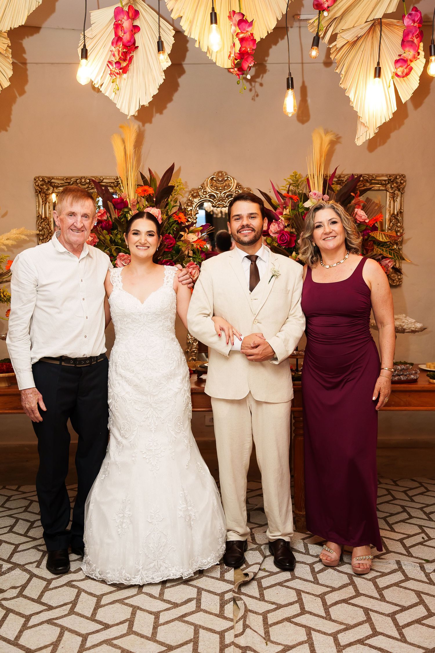 Bride and groom pose with family members at elegant wedding reception with floral decorations.