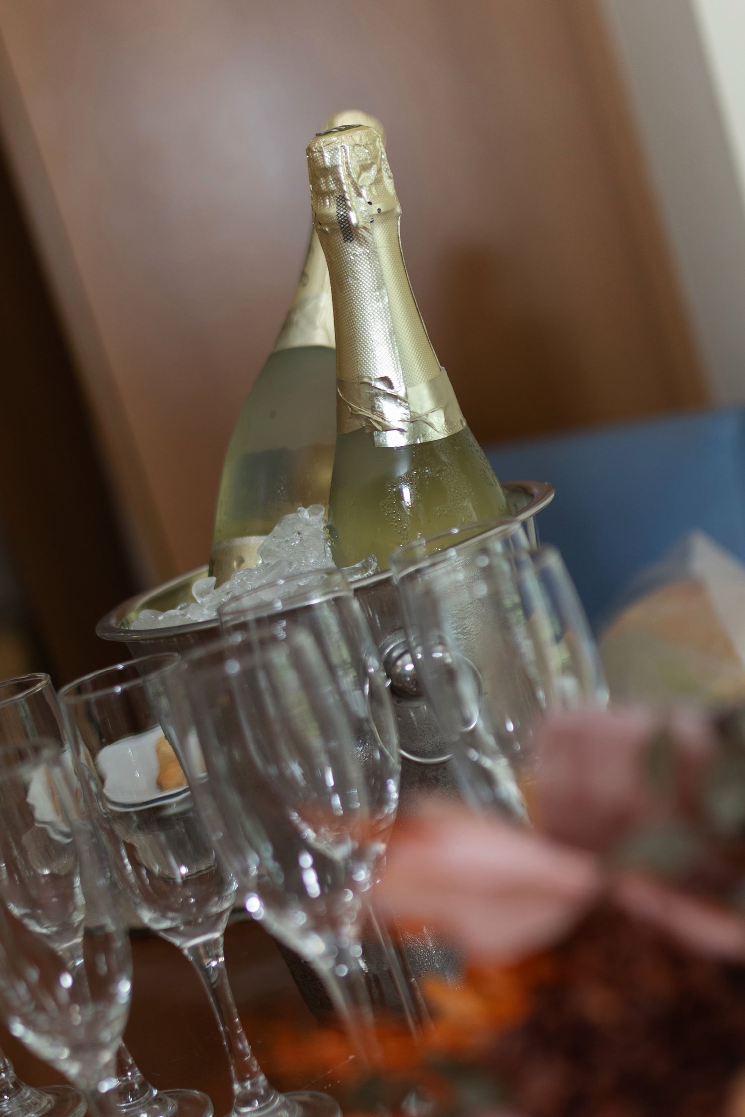 Two champagne bottles chilling in an ice bucket surrounded by elegant crystal flute glasses at a celebration event.