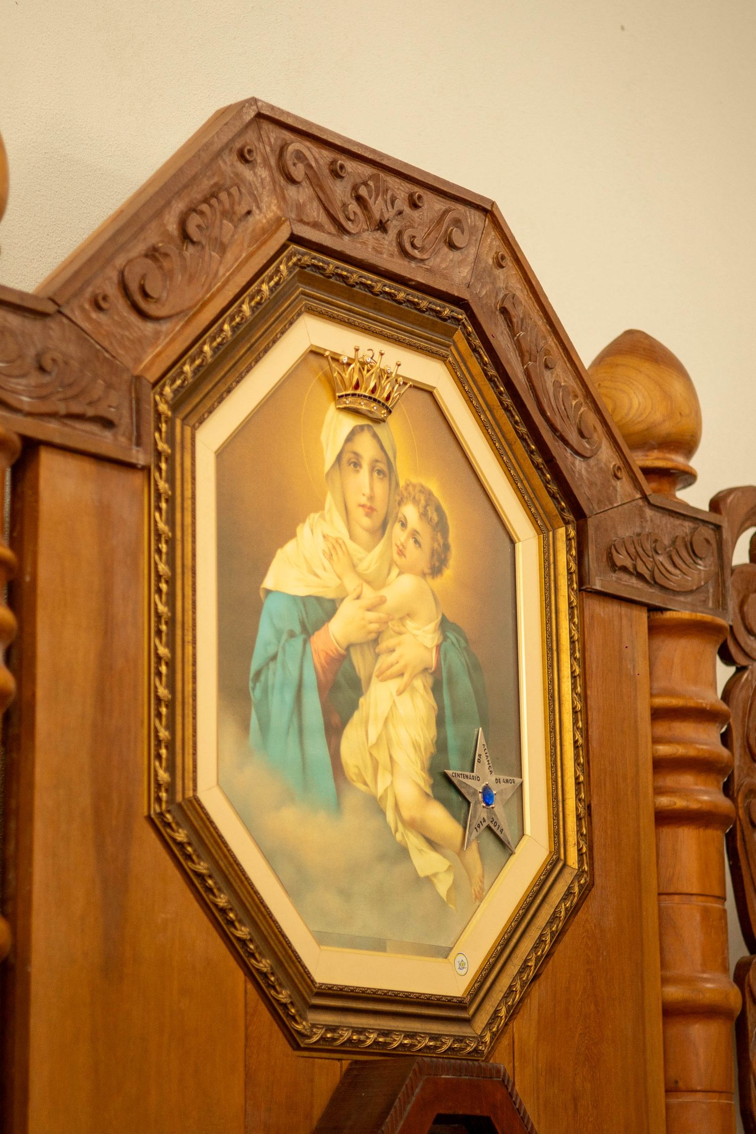 Ornate wooden octagonal frame with a Catholic painting of the Virgin Mary holding Baby Jesus, adorned with a gold crown and blue star.
