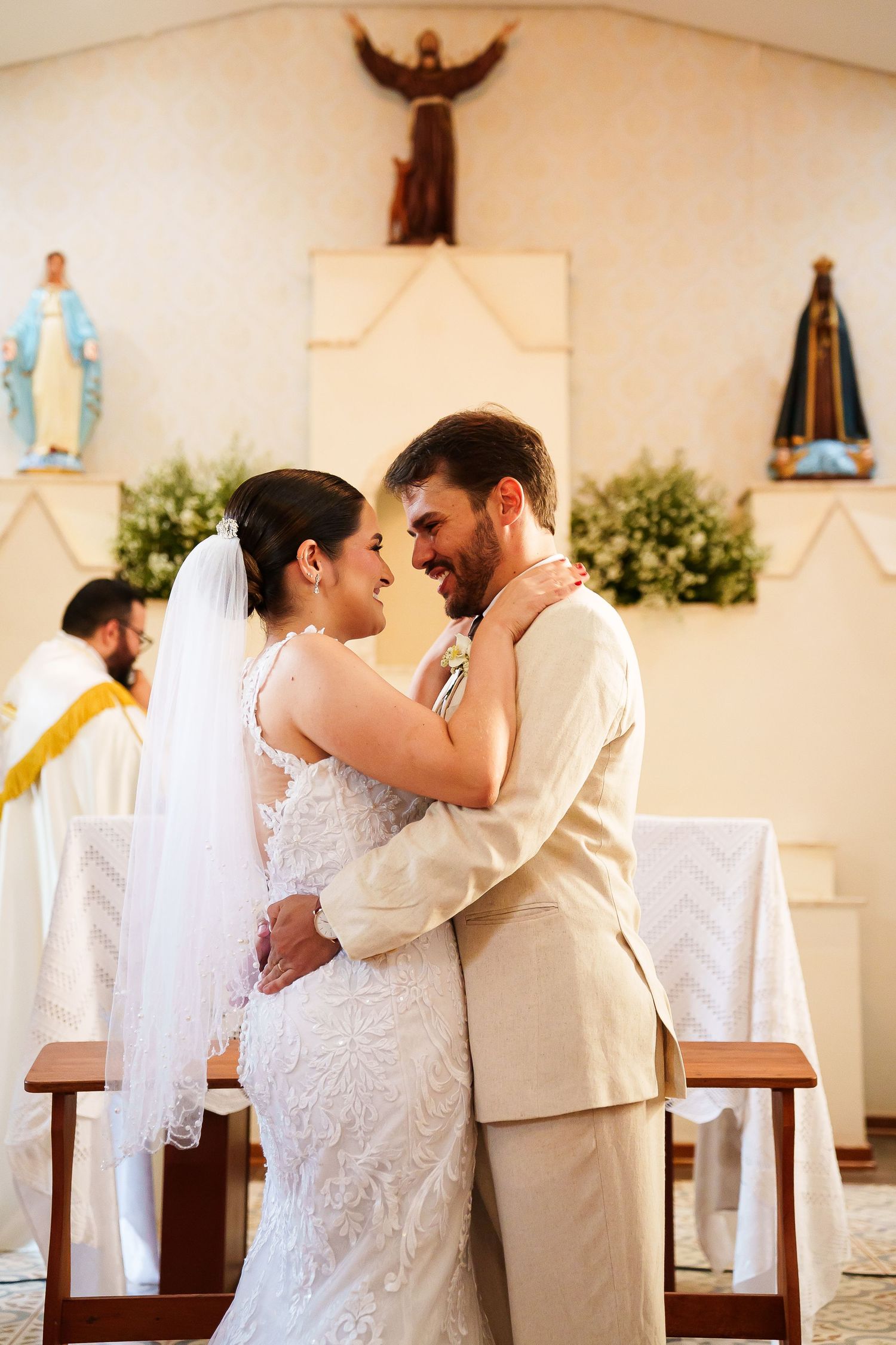 Bride and groom share a romantic embrace at the altar during their Catholic church wedding ceremony.