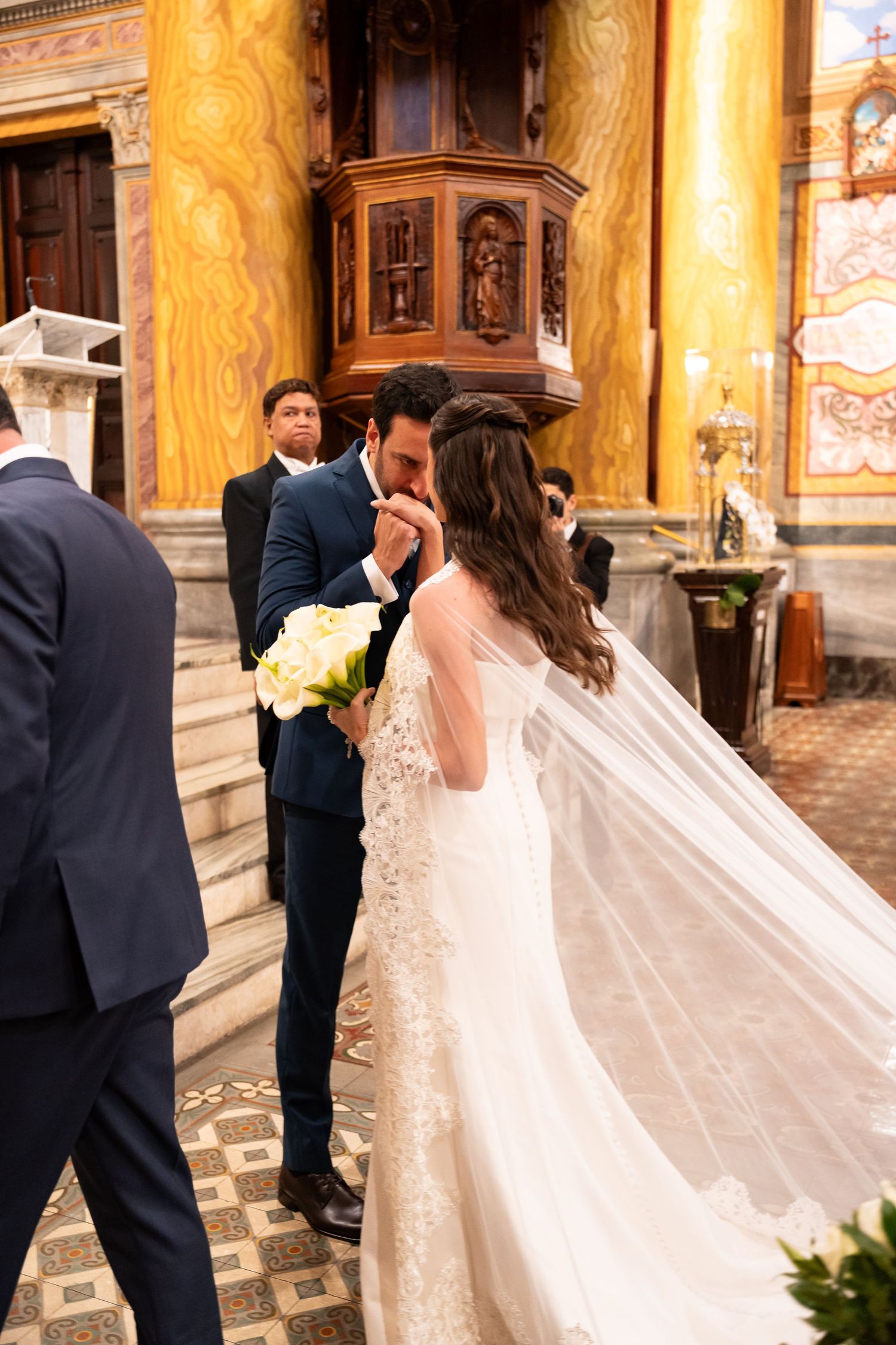Bride and groom share a romantic kiss at the altar inside an ornate church during their wedding ceremony.