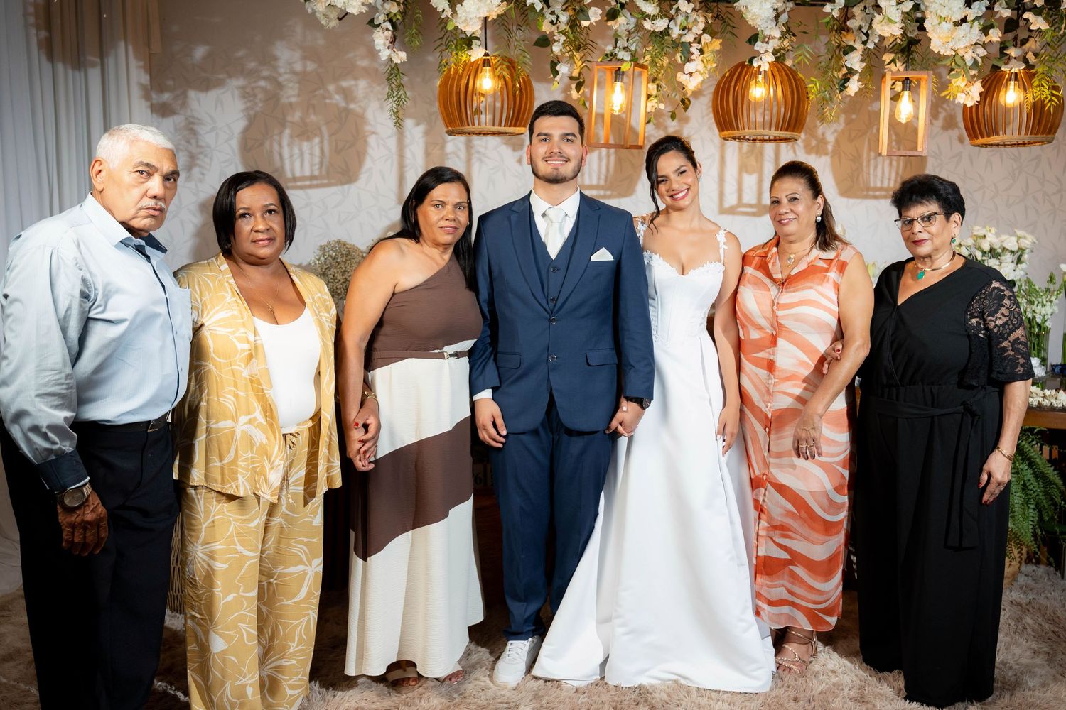 Bride and groom pose with family members at elegant wedding reception with floral decorations.