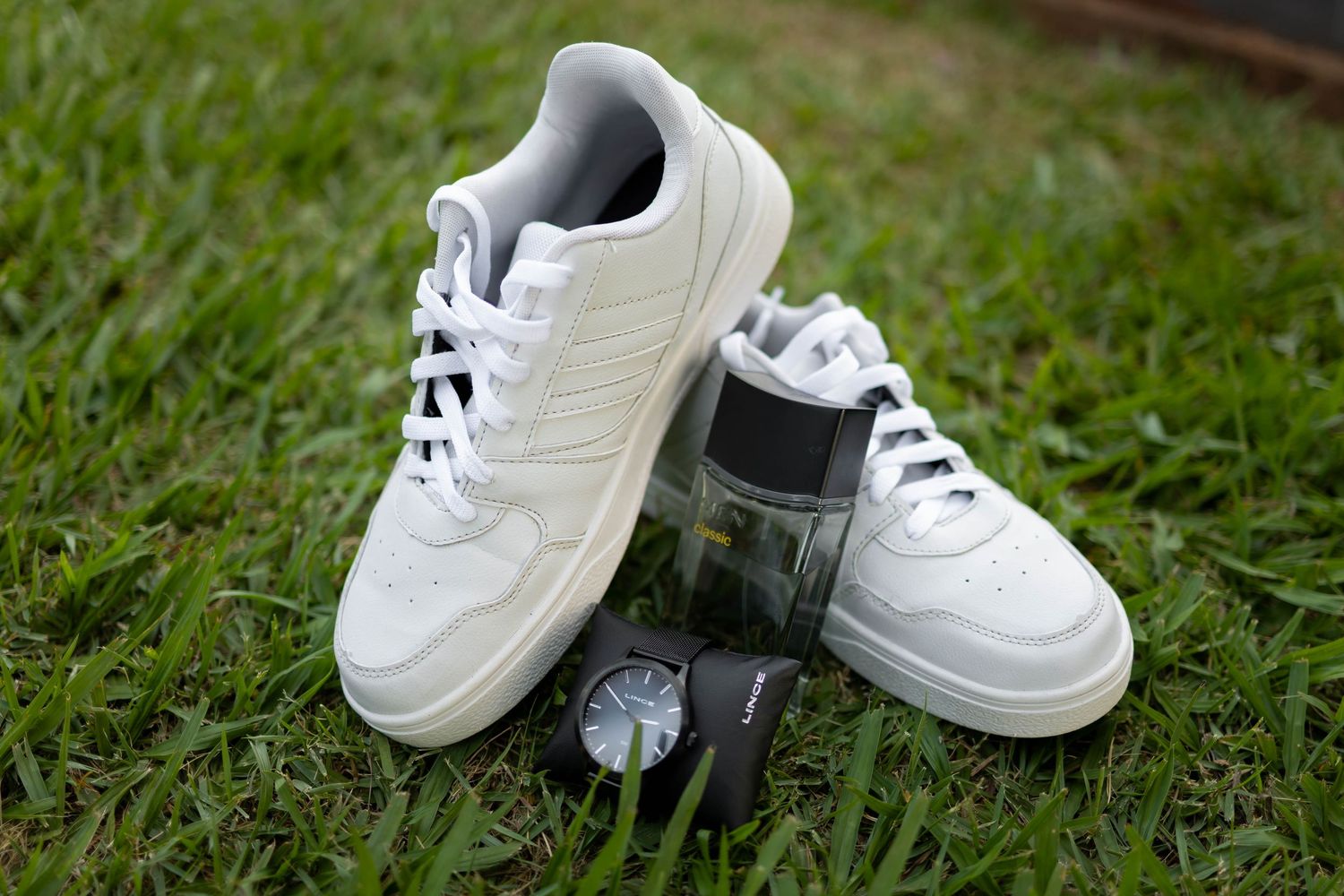 White sneakers and a watch displayed on green grass, perfect for casual streetwear styling.