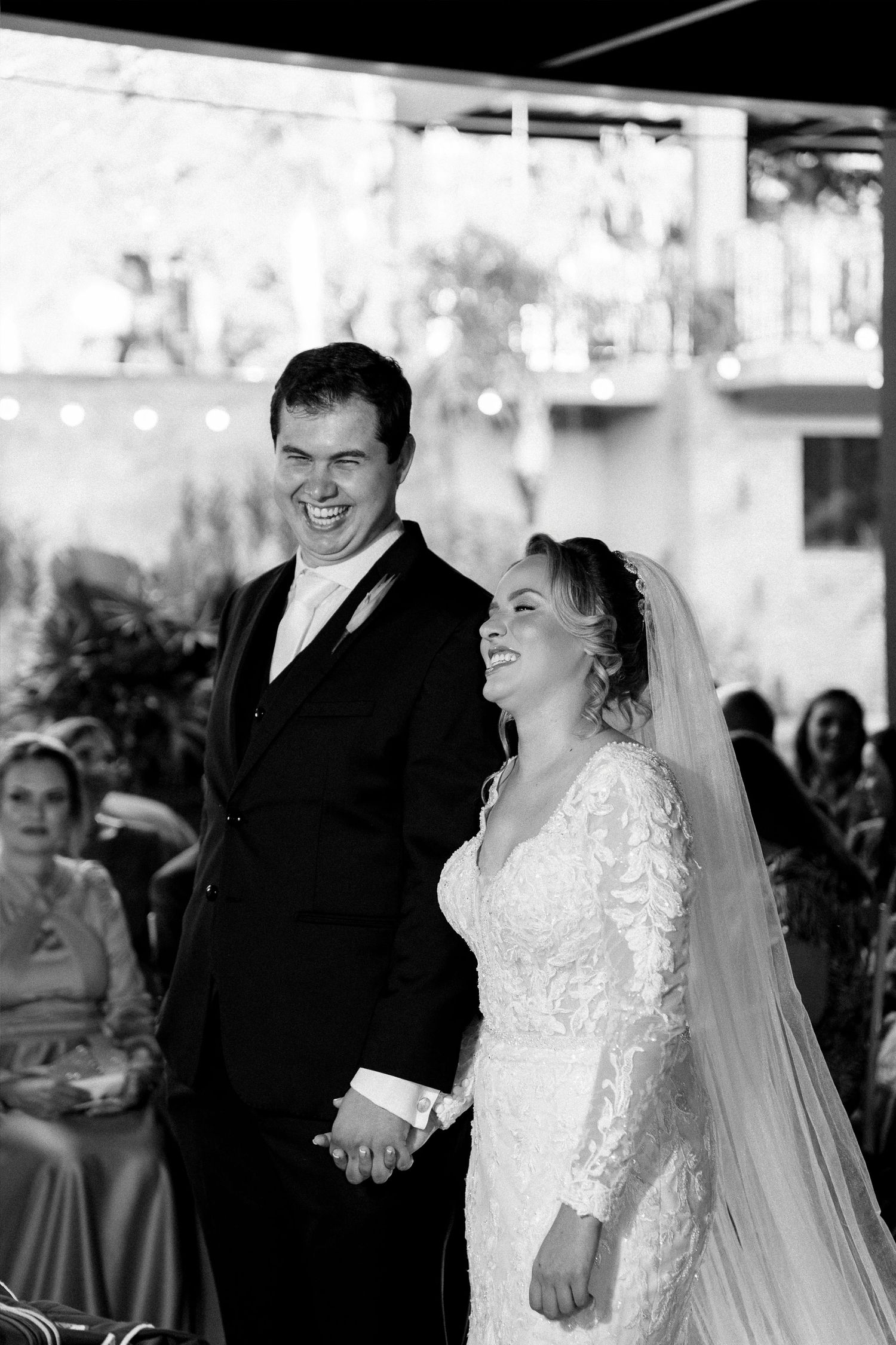 Joyful bride and groom laughing together during outdoor wedding ceremony in black and white.