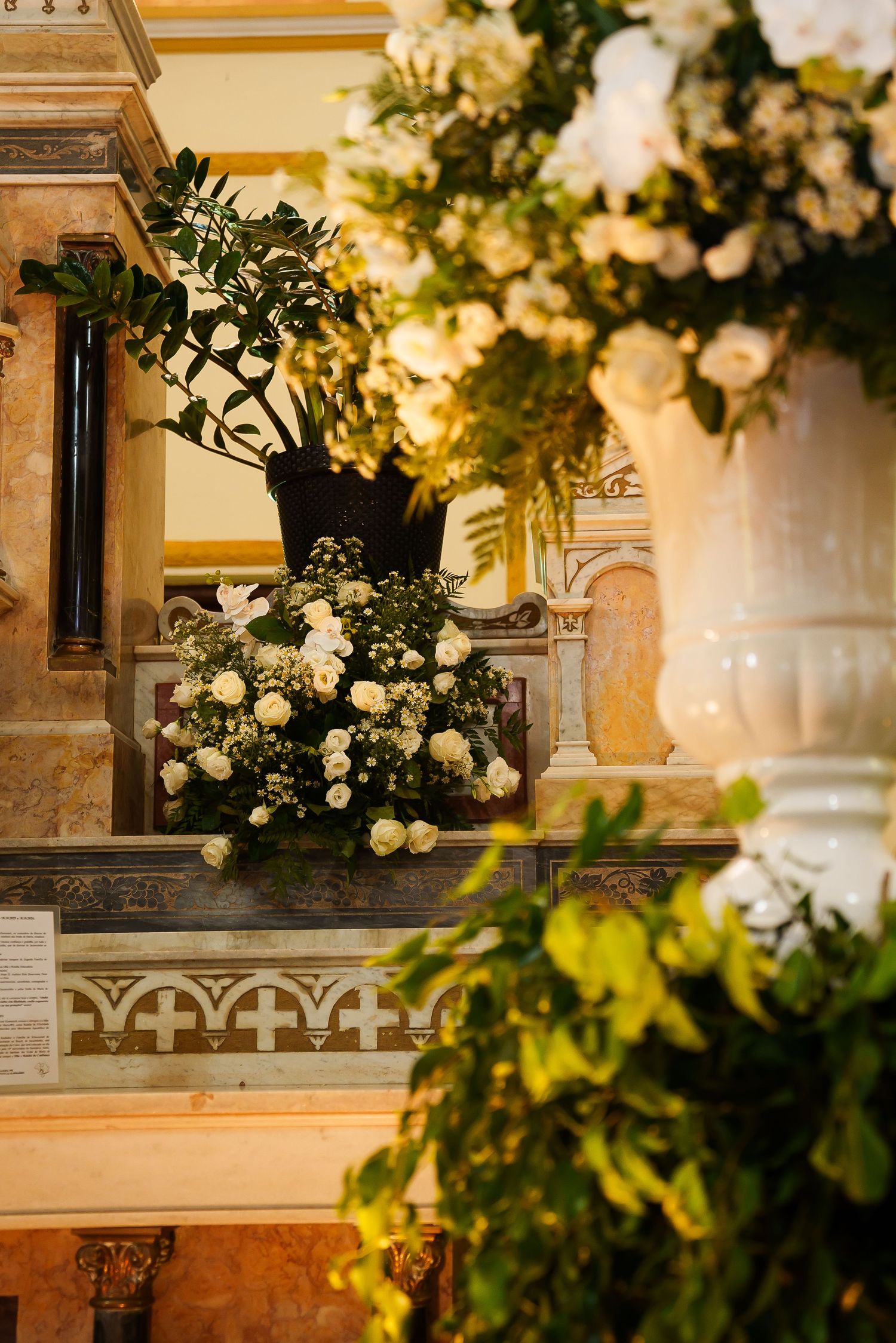 Elegant white floral arrangements adorning a ornate marble altar in a classic church interior.