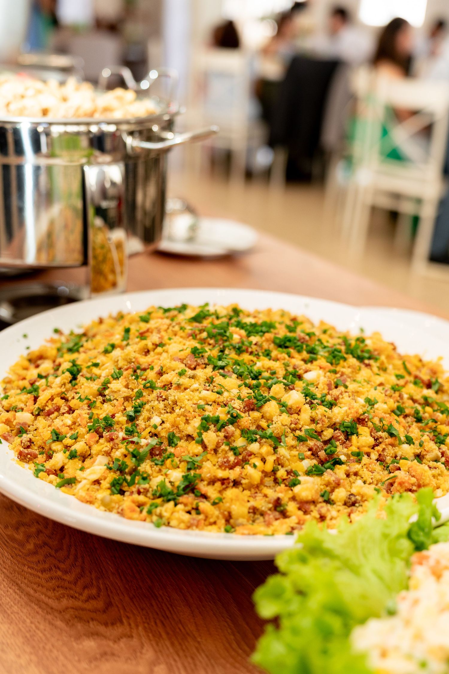 A large white plate of seasoned couscous with herbs and vegetables served at a buffet restaurant.