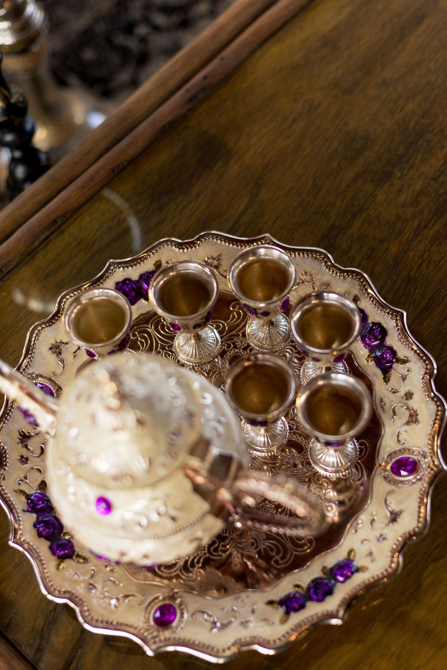 Ornate gold Turkish coffee set with purple gems on decorative tray, featuring small cups and traditional cezve pot.