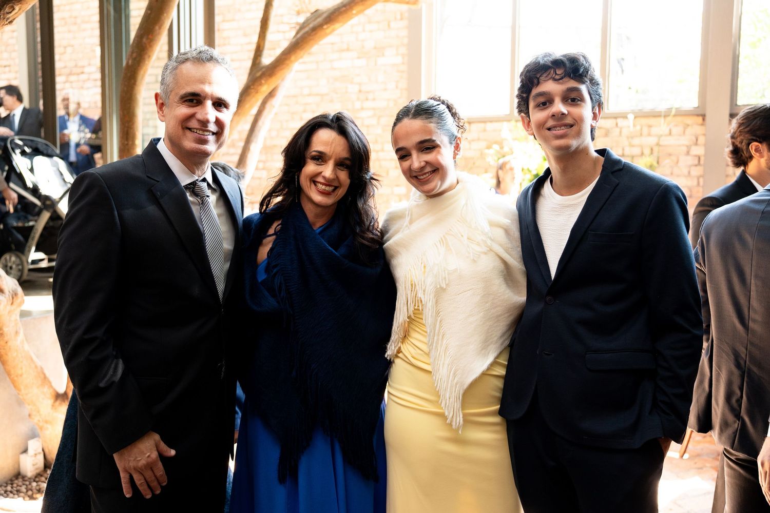 Four people smiling together at a formal event, dressed in elegant attire including blue and yellow gowns.